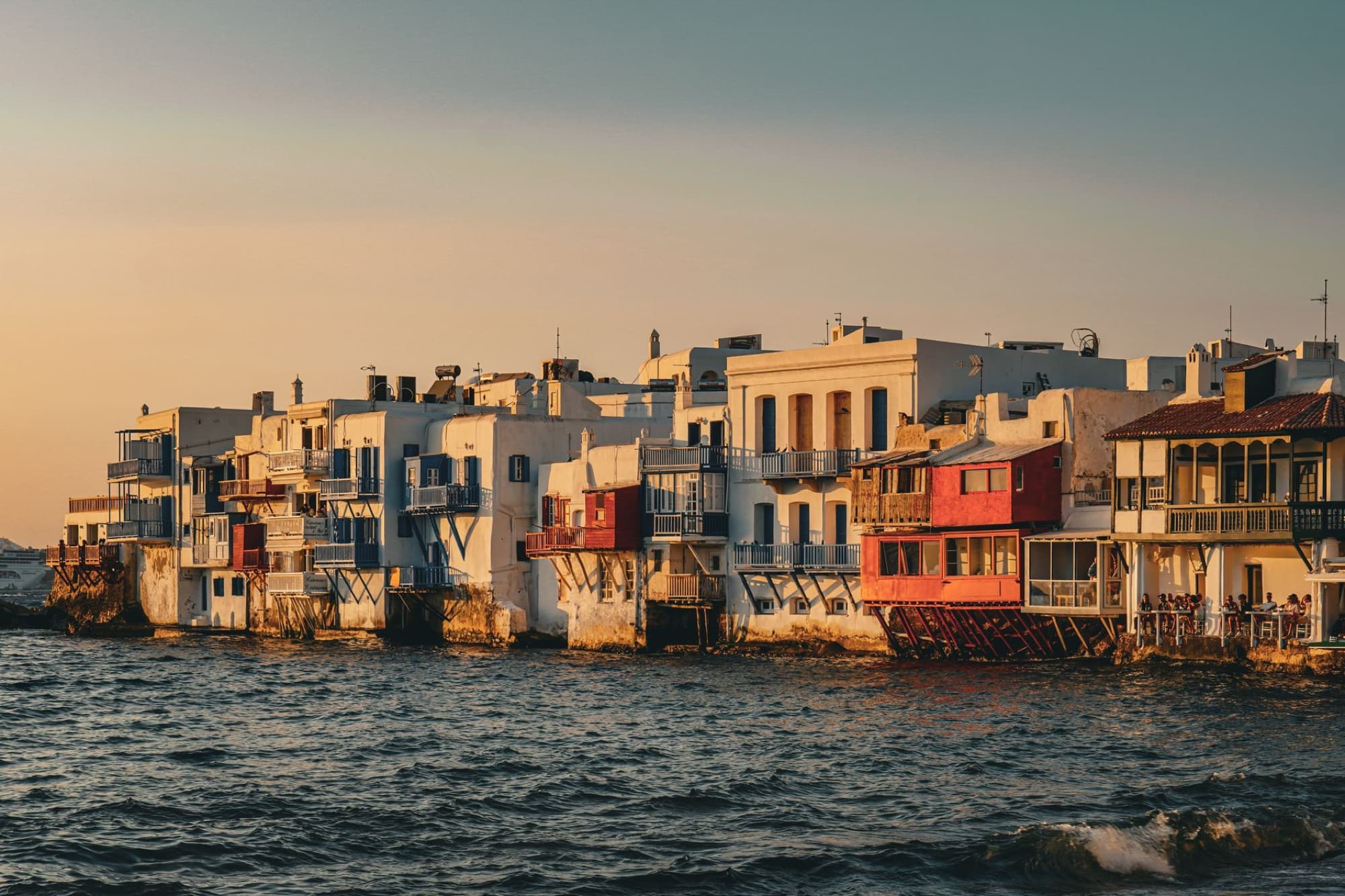 Scenic sunset over Little Venice in Mykonos, Greece, showcasing vibrant architecture by the sea.