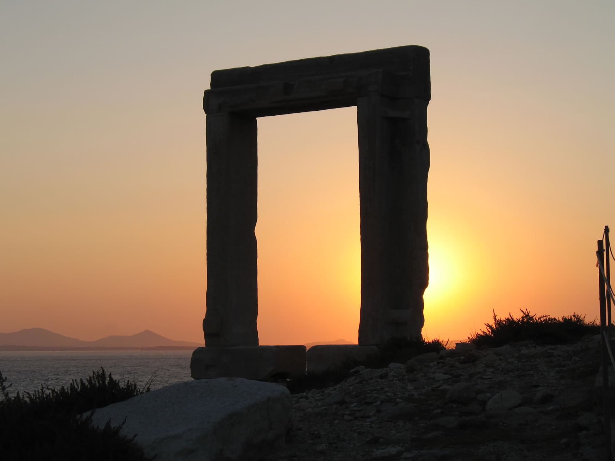 The ancient Portara silhouetted against a stunning sunset in Naxos, Greece.