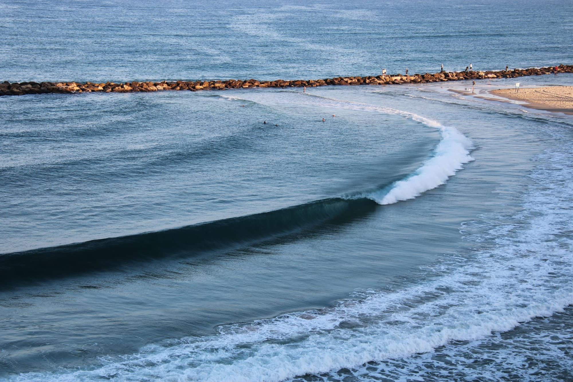 Breathtaking view of ocean waves and breakwater at Netanya Beach, Israel.