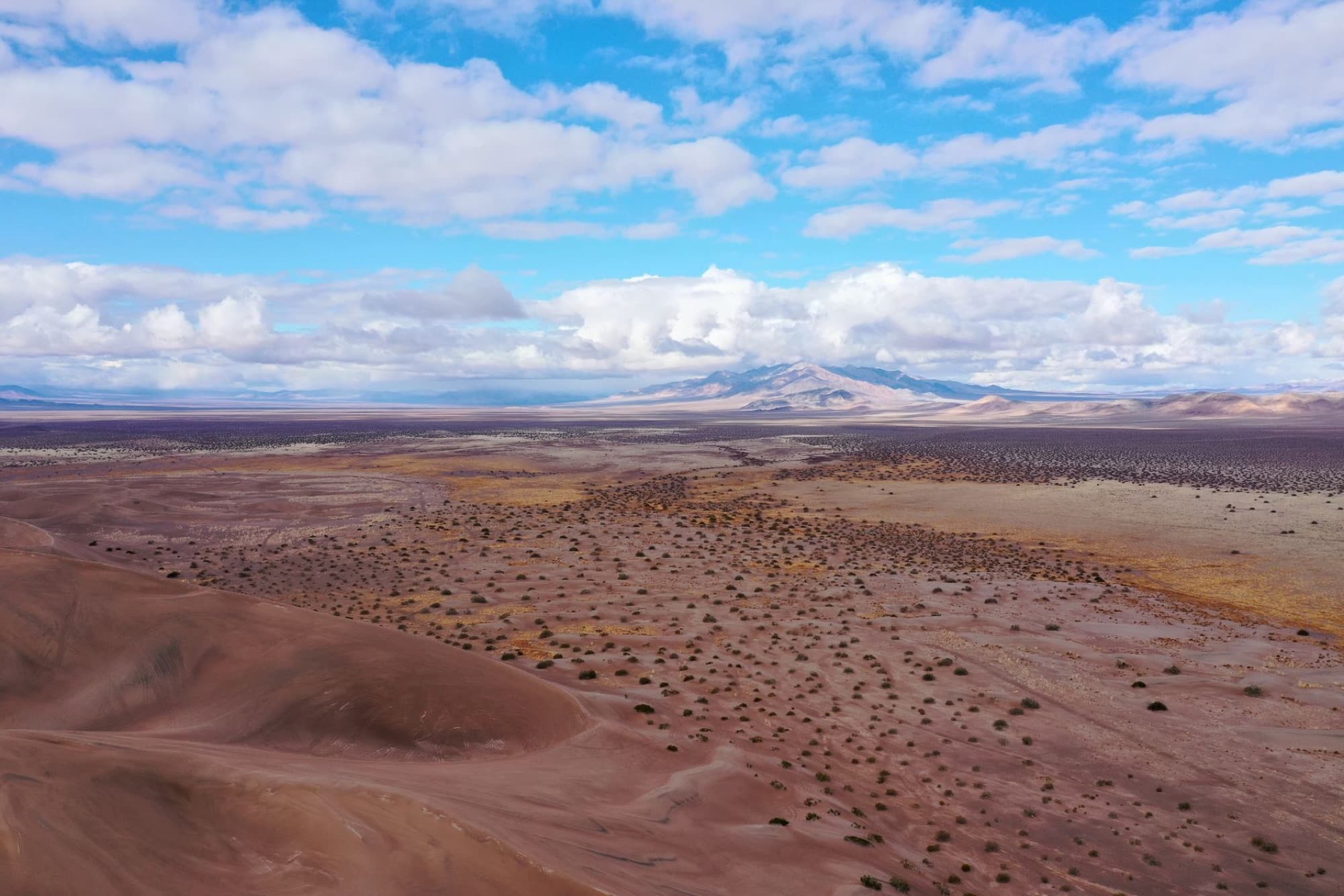 An expansive aerial view of the desert landscape in Beatty, Nevada with clouds and distant mountains.