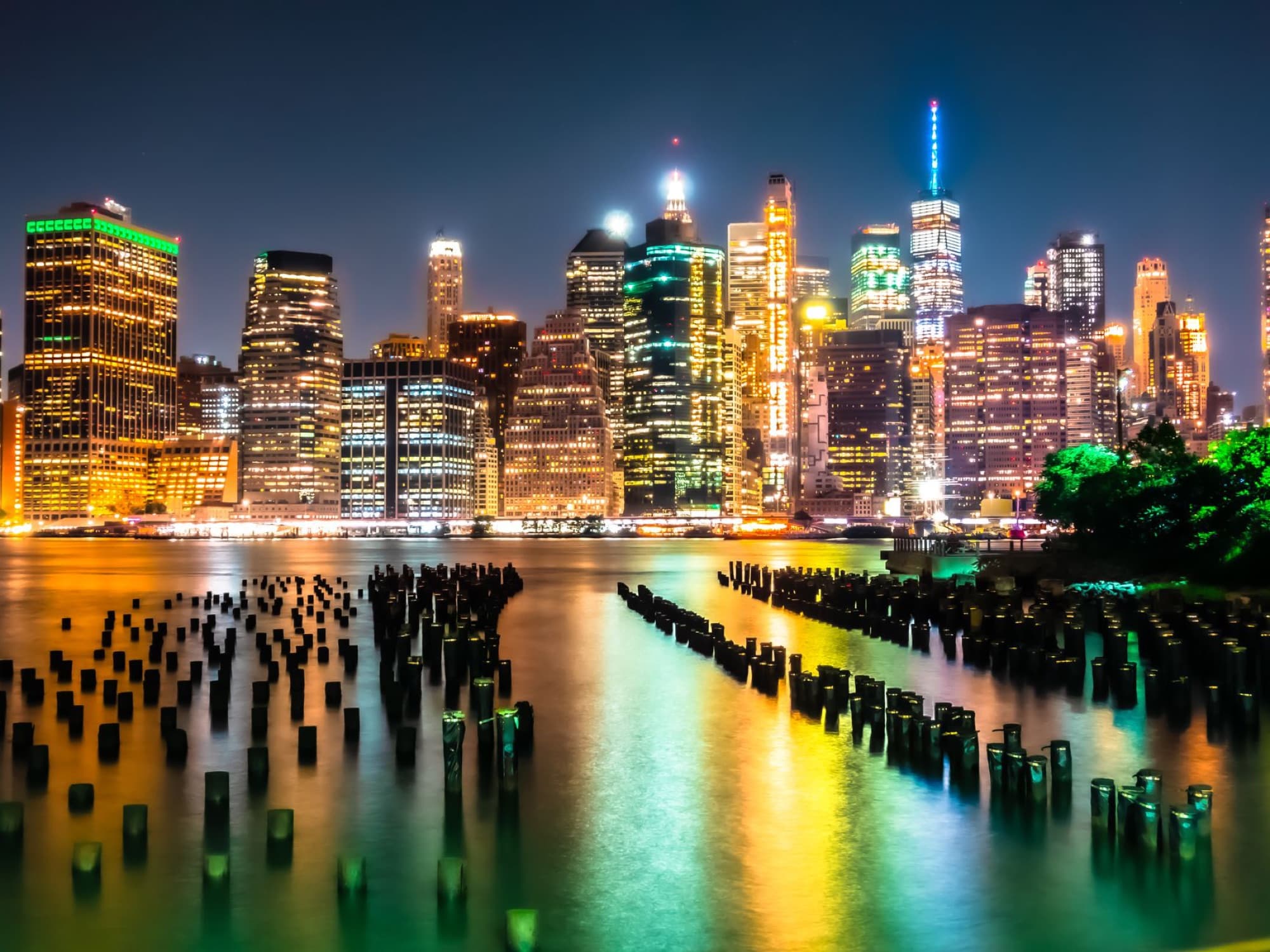 Captivating night panorama of New York City skyline with vibrant city lights reflecting on the river.