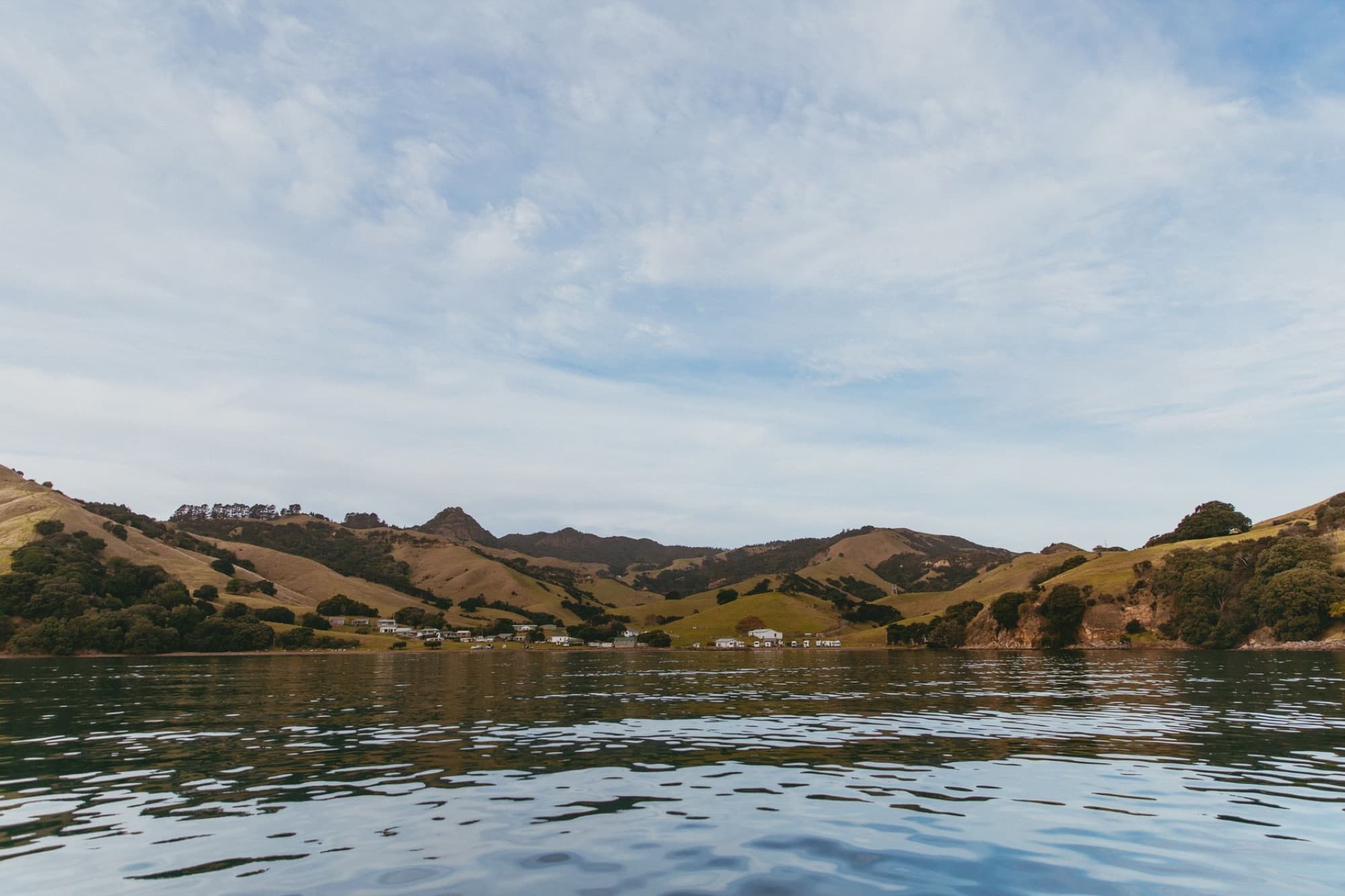 Serene landscape of Kereta Bay in Waikato, New Zealand with hills and coastline.