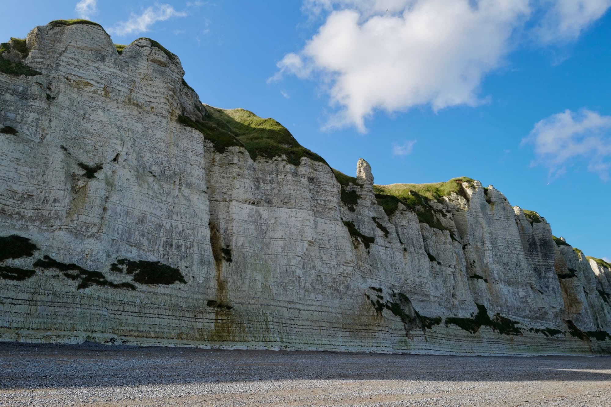 Stunning view of Fécamp's white cliffs with green tops and blue sky in Normandy, France.