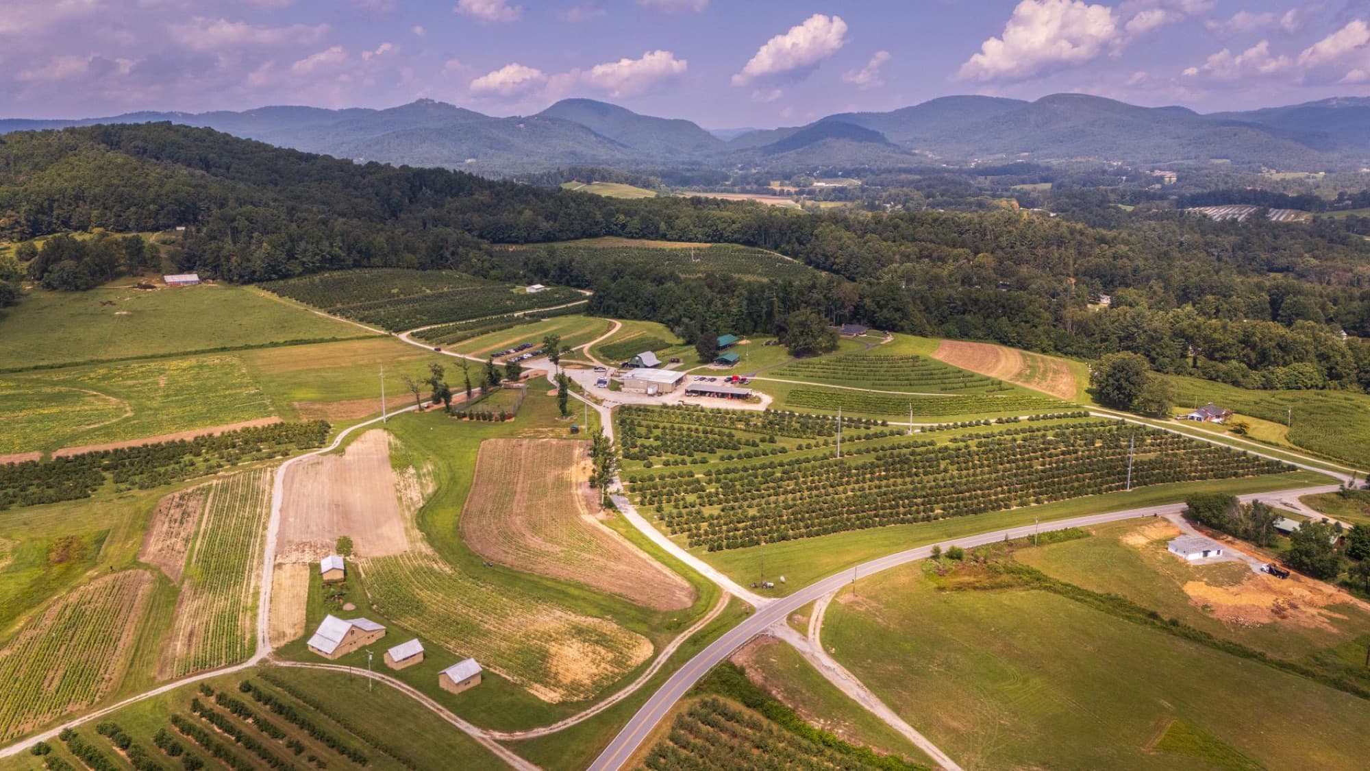 Aerial shot of farmland surrounded by mountains in North Carolina's Blue Ridge region.