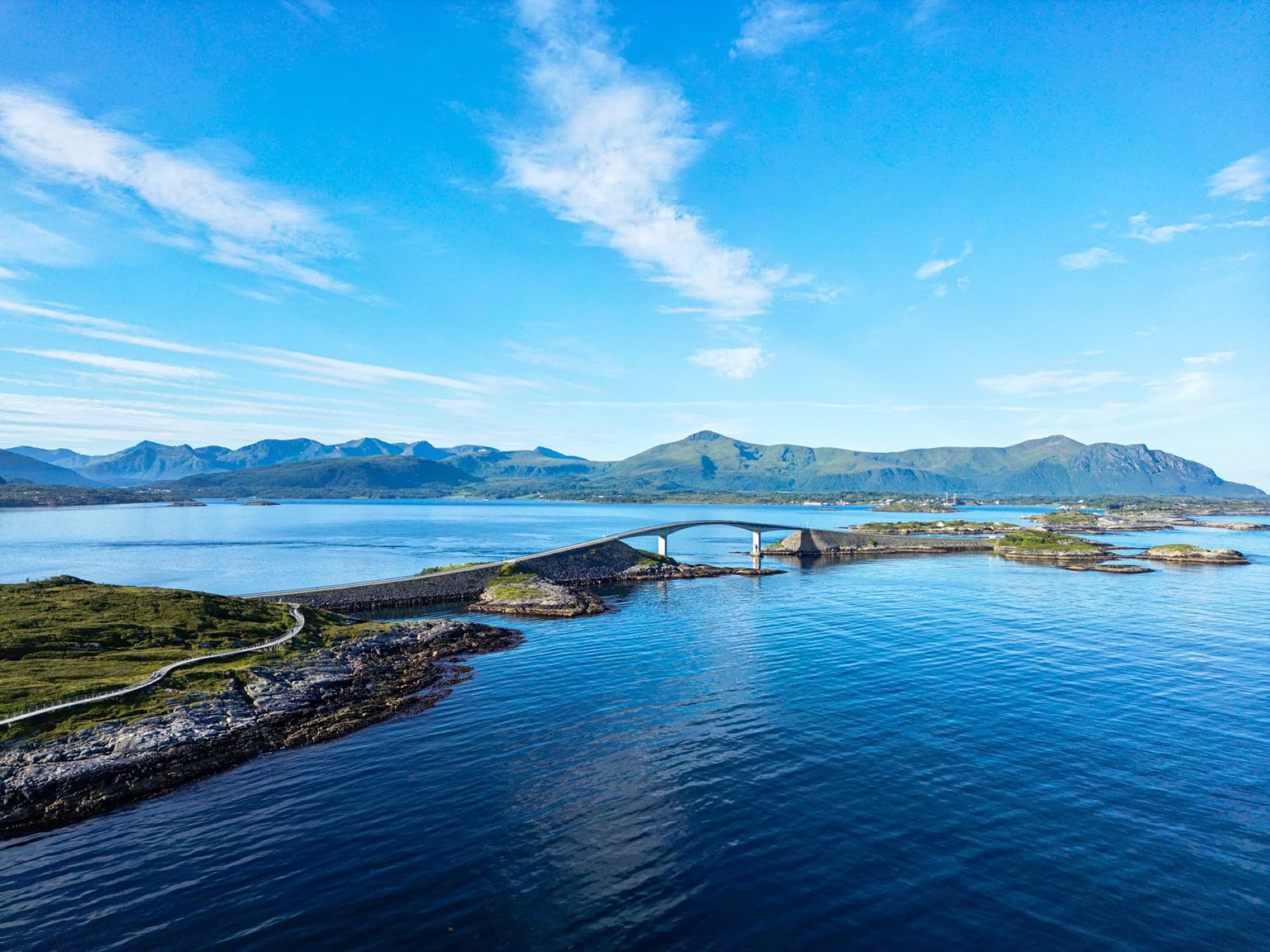 A breathtaking aerial shot of the iconic Atlantic Ocean Road Bridge in Norway against a scenic coastal backdrop.