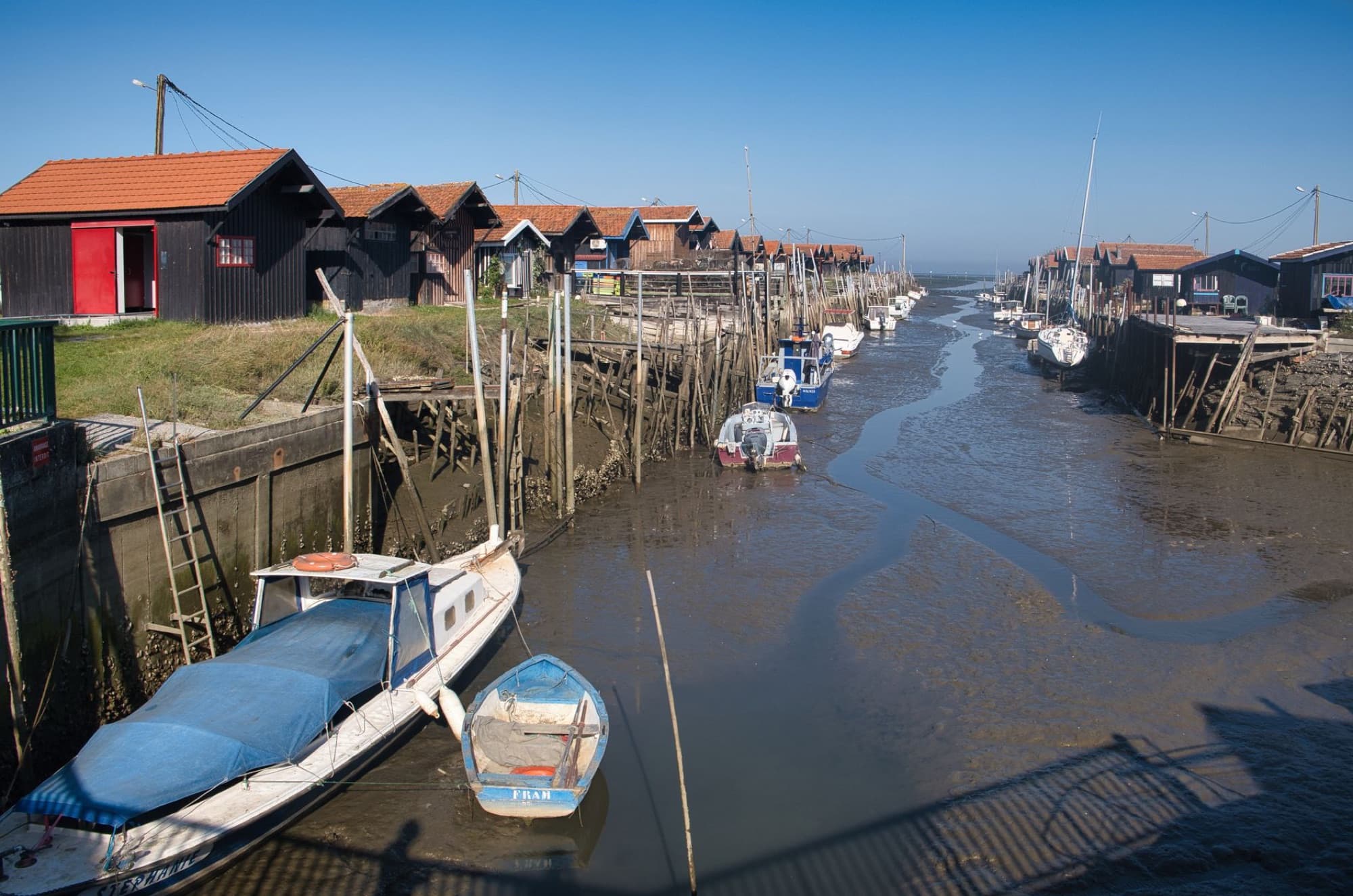 Aerial view of a picturesque coastal village with traditional houses and moored boats in a shallow river.