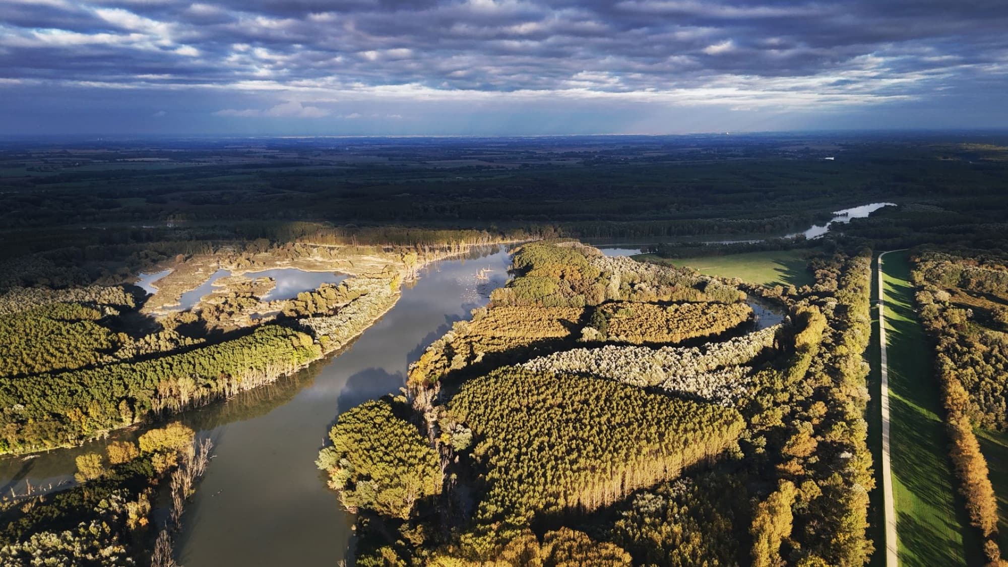Aerial view of the scenic Danube River winding through lush forests in Hungary, captured during autumn.