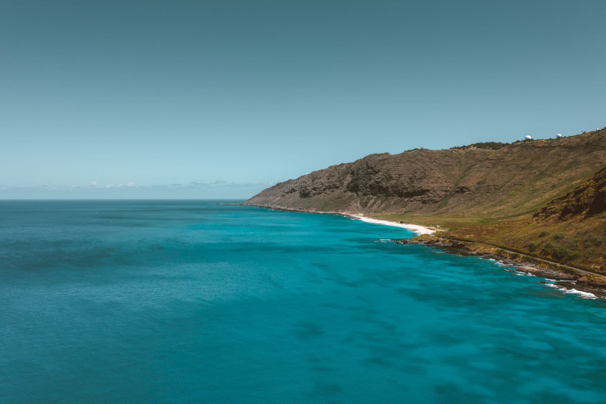 Stunning aerial view of the Oahu coast with clear blue waters and rugged cliffs.