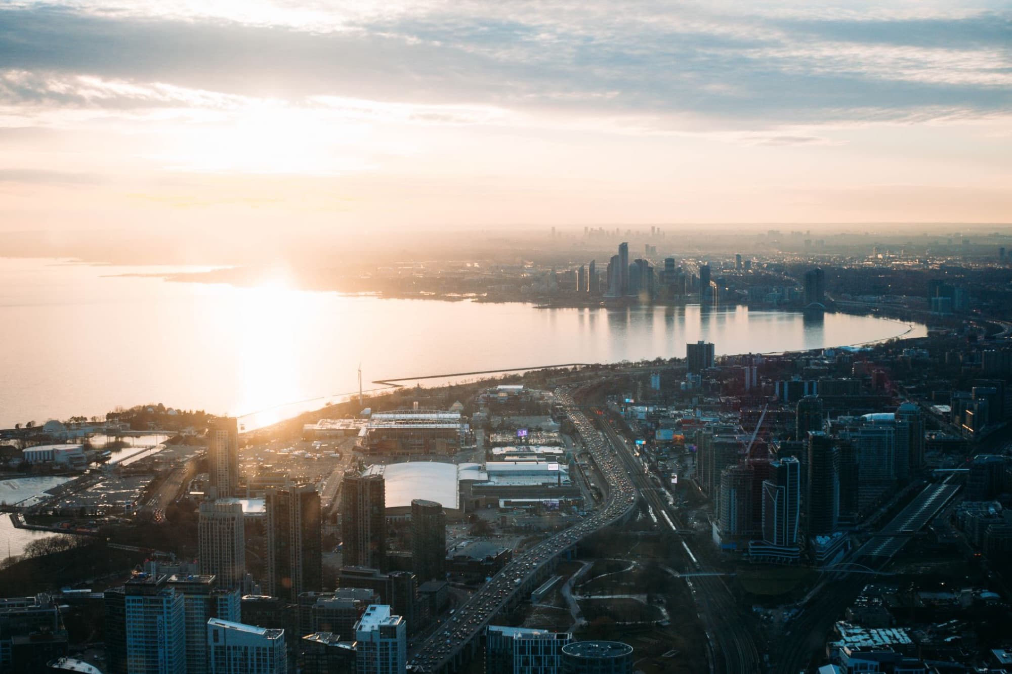 Breathtaking aerial view of Toronto's skyline during sunrise, highlighting Lake Ontario and urban architecture.