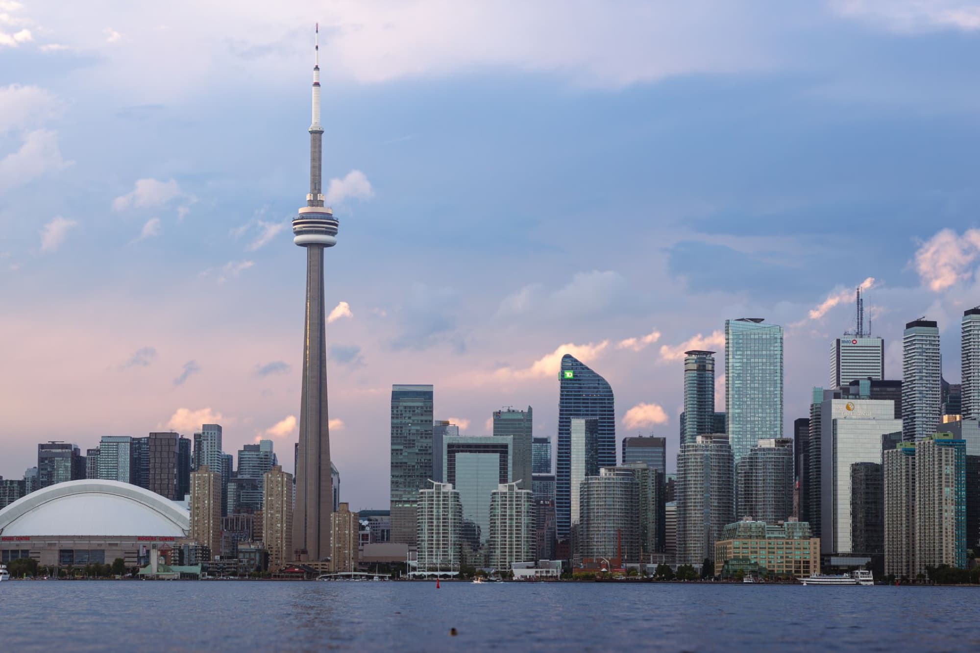 Scenic view of Toronto skyline with CN Tower at sunset, over Lake Ontario.