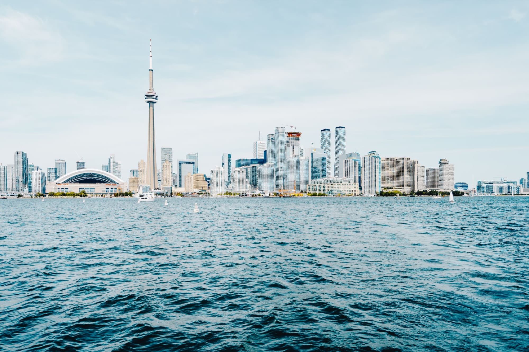 Panoramic view of Toronto's skyline with CN Tower and Lake Ontario on a clear day.