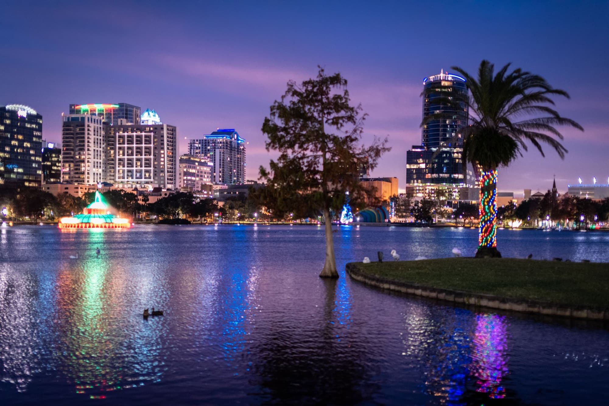 Vibrant Orlando city skyline reflected in Lake Eola at twilight, capturing the festive atmosphere.