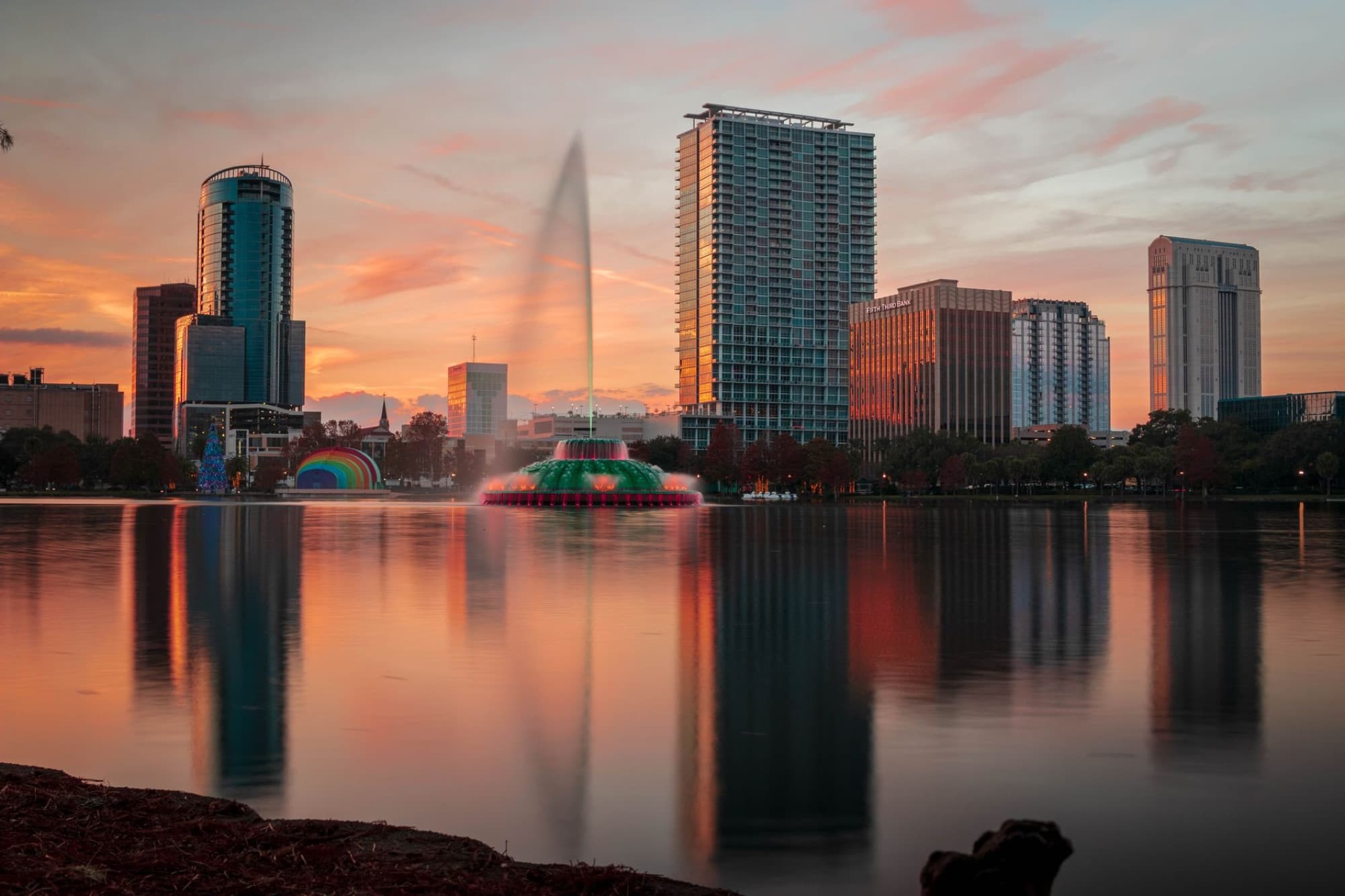 Beautiful view of Orlando skyline during sunset with Lake Eola fountain reflecting on the water.
