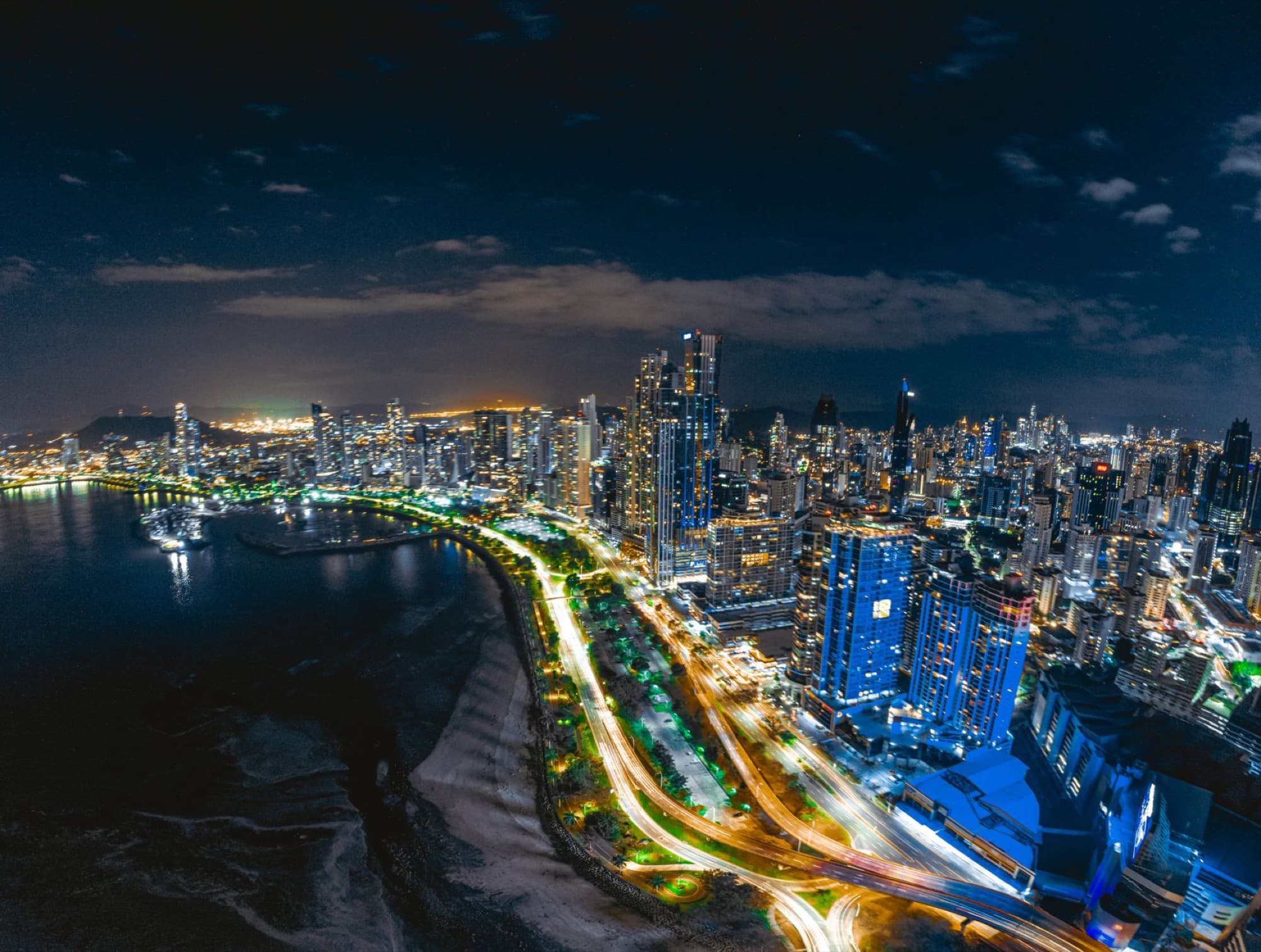 Stunning aerial view of Panama City's illuminated skyline and coastline at night.