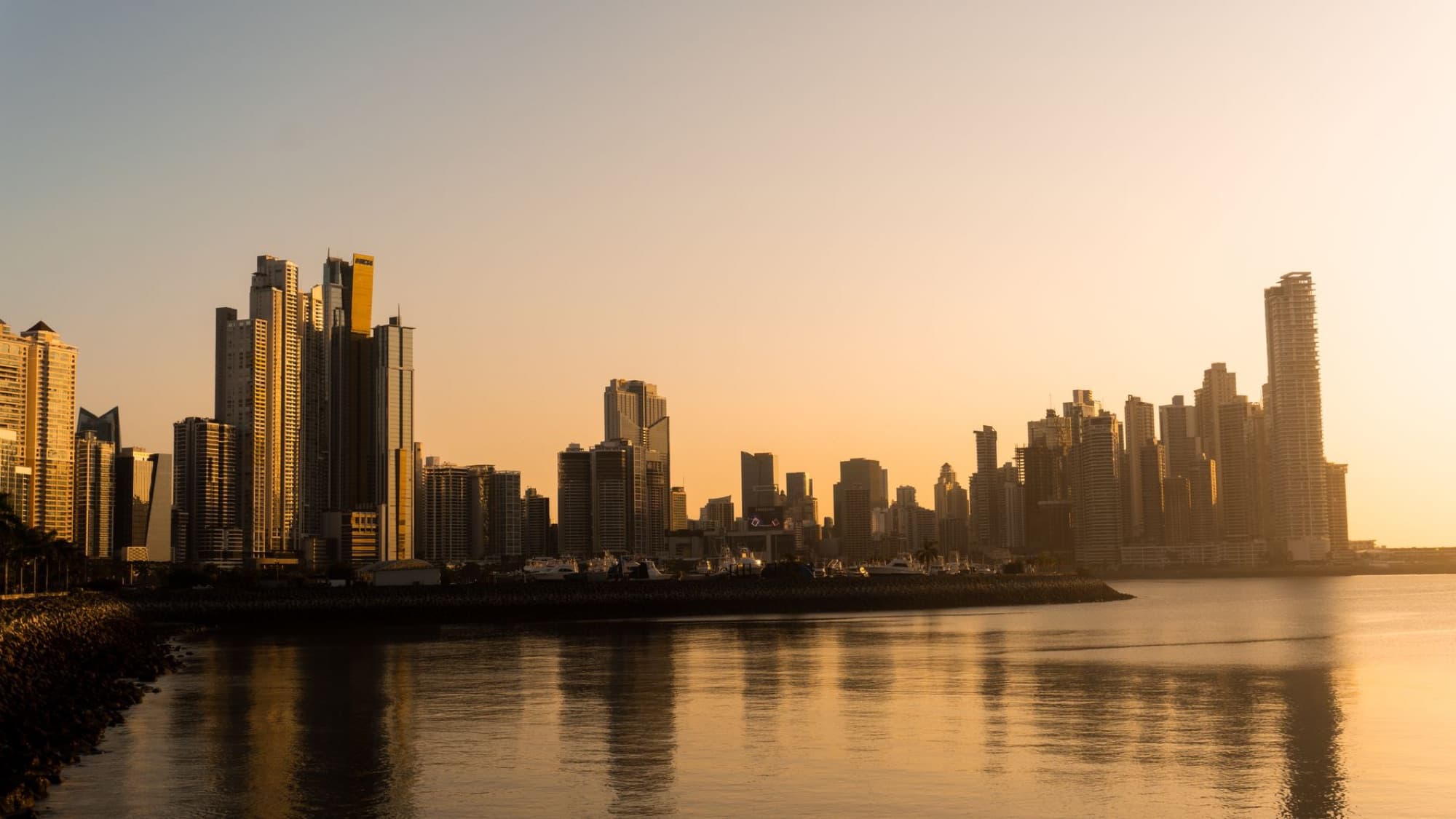 Stunning view of Panama City's modern skyline at sunrise, reflecting on the sea.