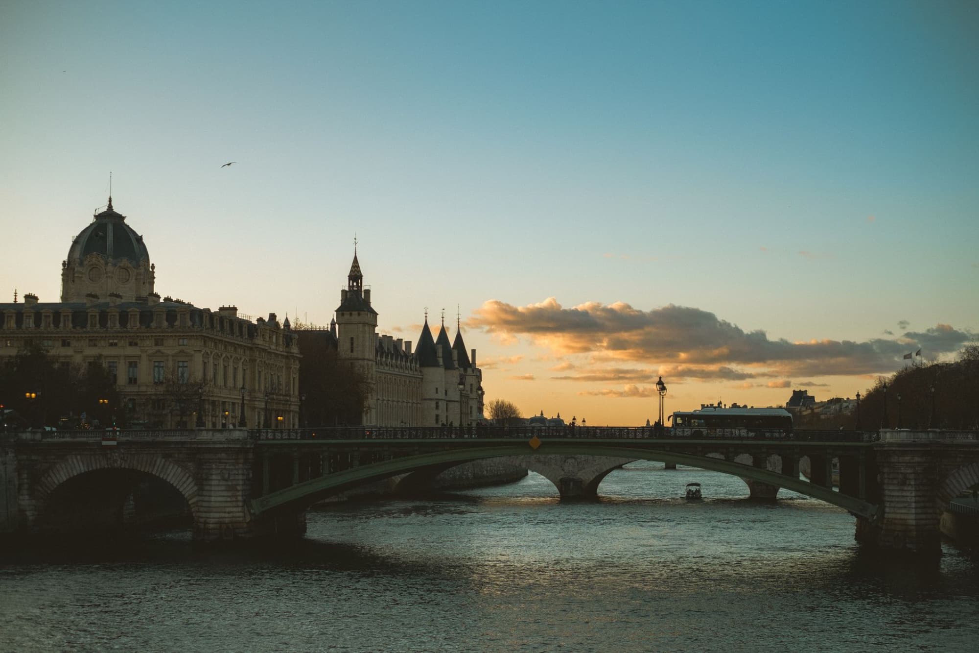 Stunning view of a bridge over Seine River in Paris at sunset, capturing the skyline and river ambiance.