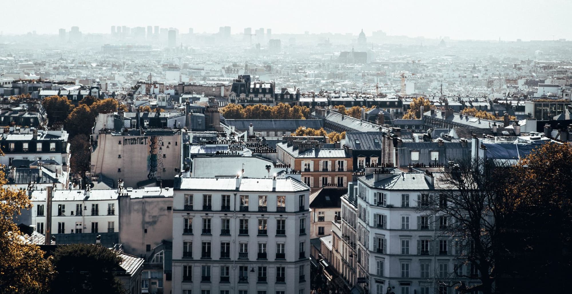 Aerial view of Paris with classic architecture under a hazy sky, capturing the city's charm.