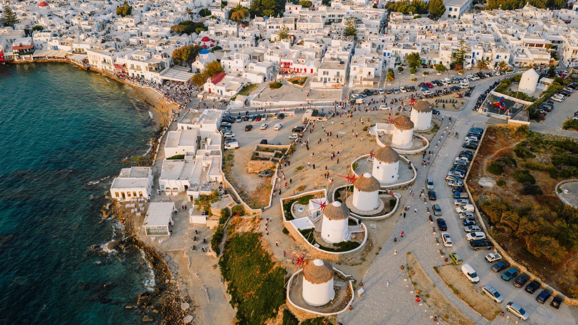 Stunning aerial view of the famous windmills of Mykonos, Greece, at sunset, surrounded by whitewashed buildings.