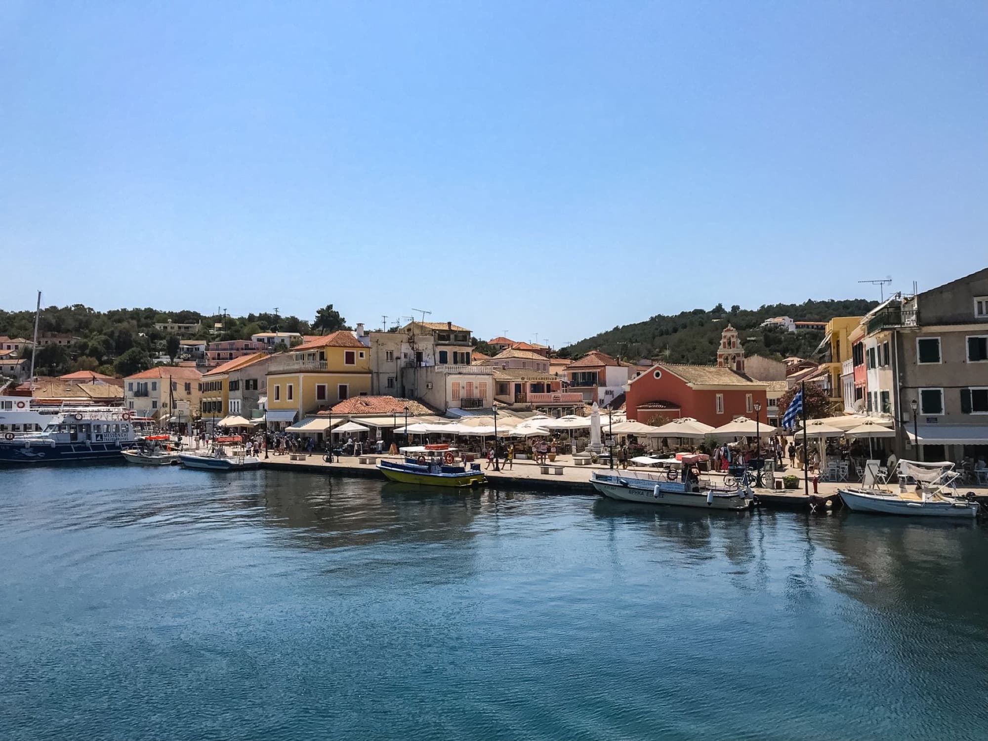 Scenic waterfront view of Paxos village, Greece, with vibrant buildings and serene water.