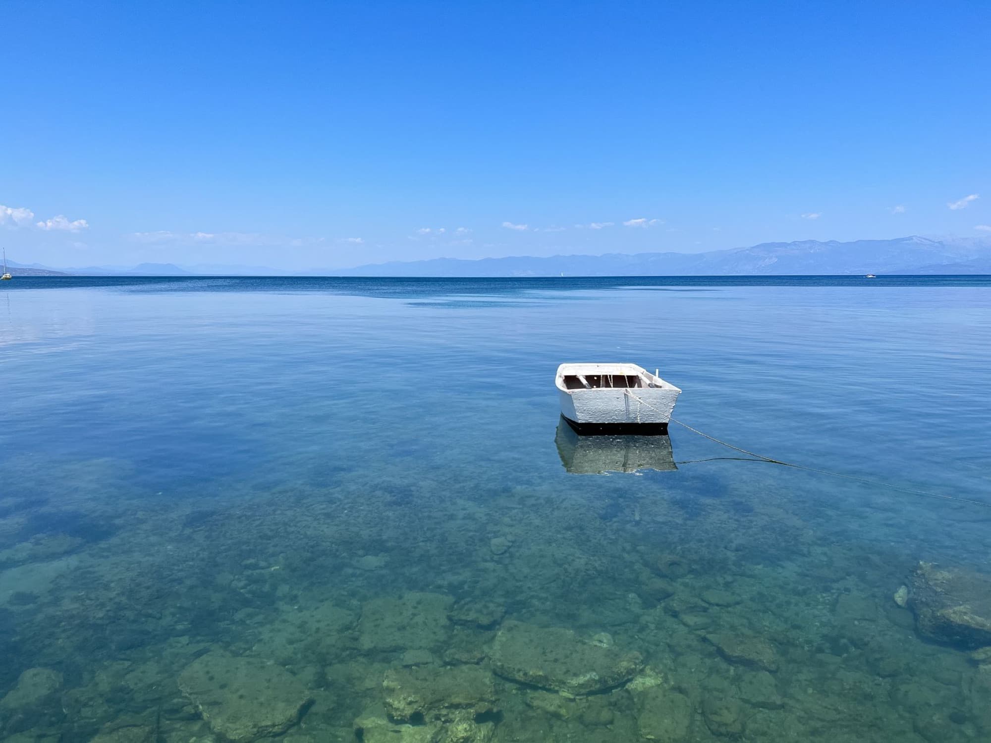 Tranquil scene of a solitary boat floating on clear waters in Peloponnese, Greece.