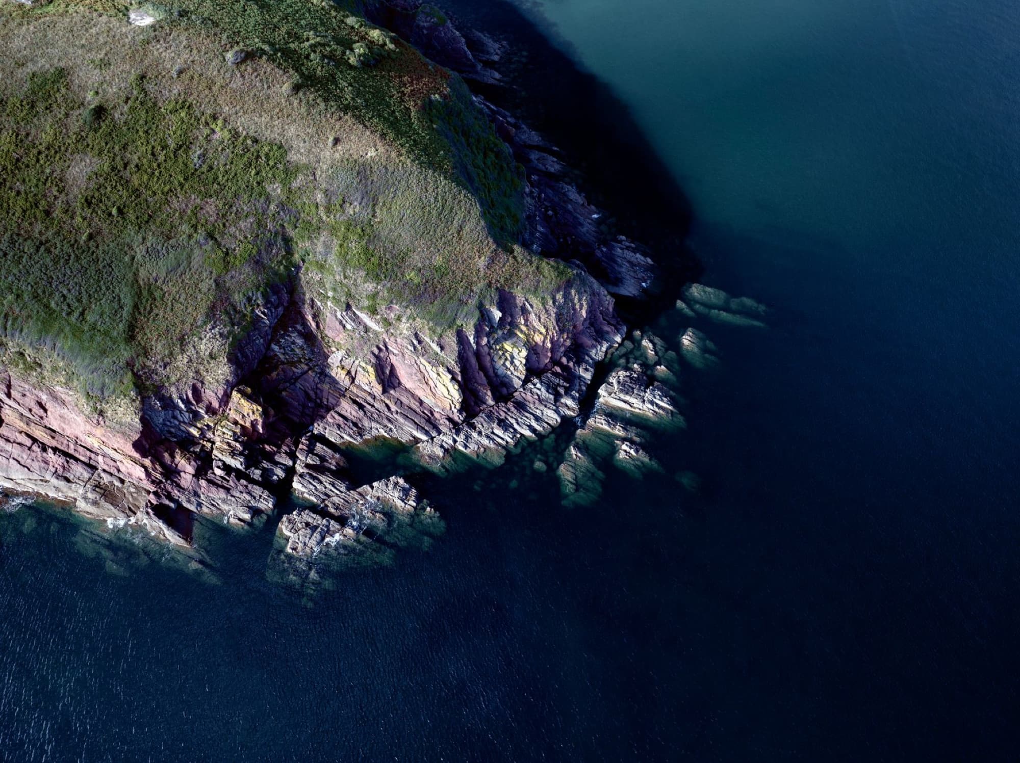 Stunning aerial view of the rocky coastline in Pembrokeshire, Wales with vibrant colors and clear waters.