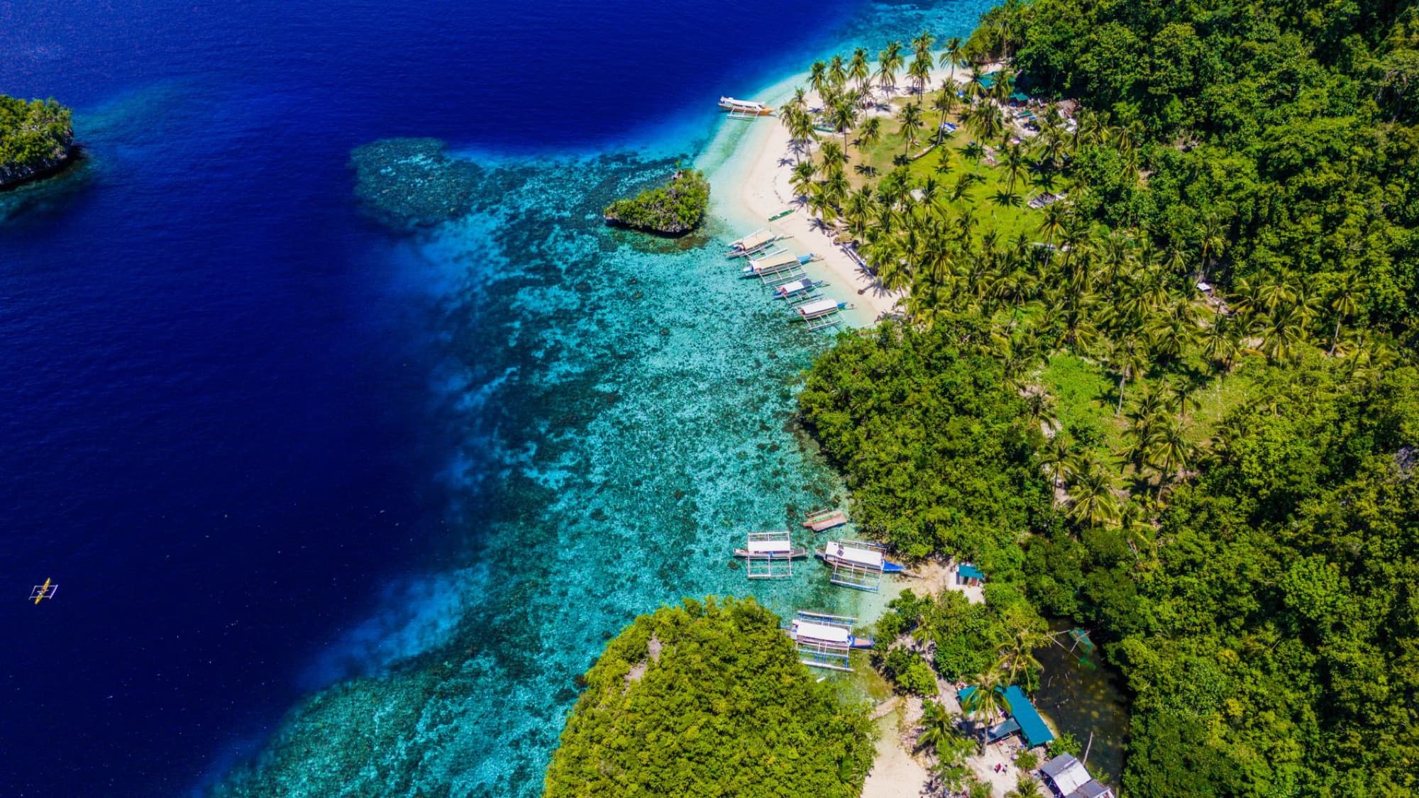 Stunning aerial vista of a turquoise beach in Caraga, Philippines, surrounded by lush greenery.