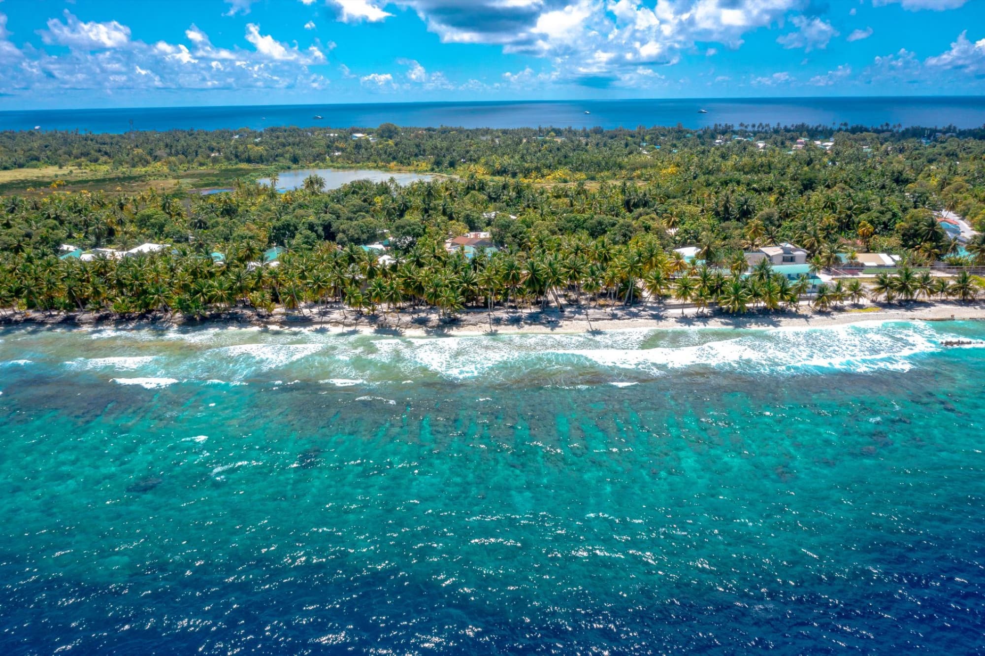 Stunning aerial view of a tropical island coastline with turquoise waters and lush greenery in the Maldives.