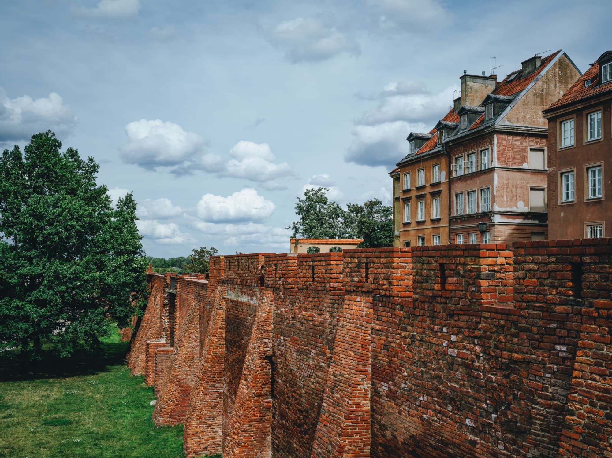 A scenic view of a historic brick wall in the Old Town of Warsaw, Poland with residential buildings.