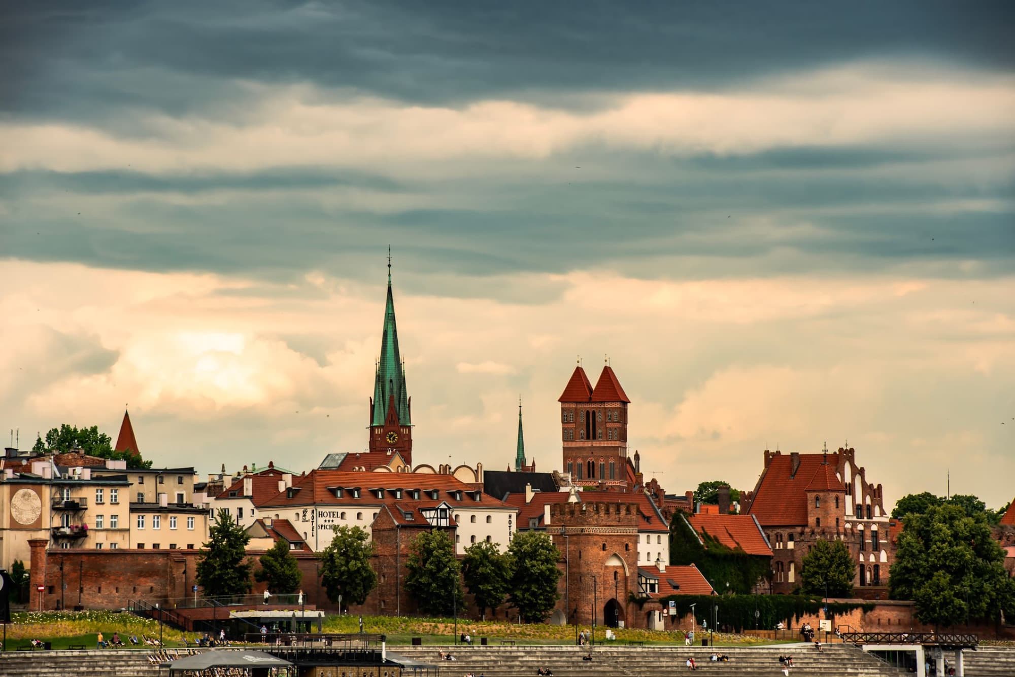 Beautiful sunset over Torun cityscape featuring historic buildings and church towers in Poland.