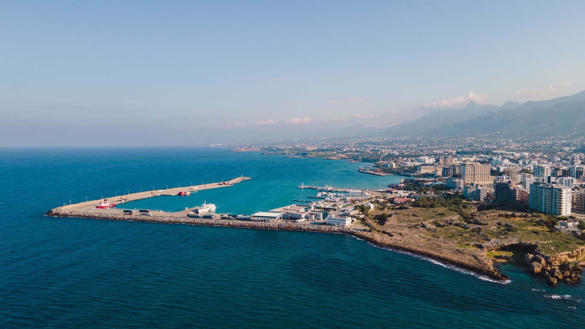 Aerial view of a coastal city with a vibrant harbor and a clear blue sky.