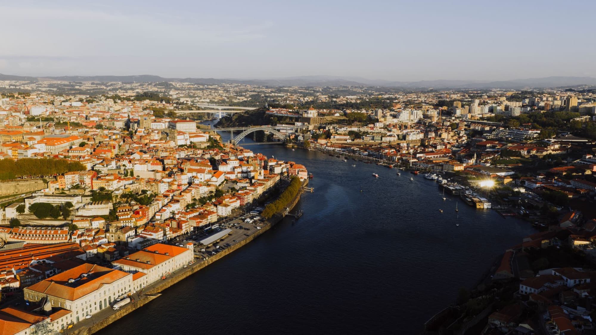Capture the breathtaking aerial view of Porto, Portugal with its iconic Douro River at sunset.