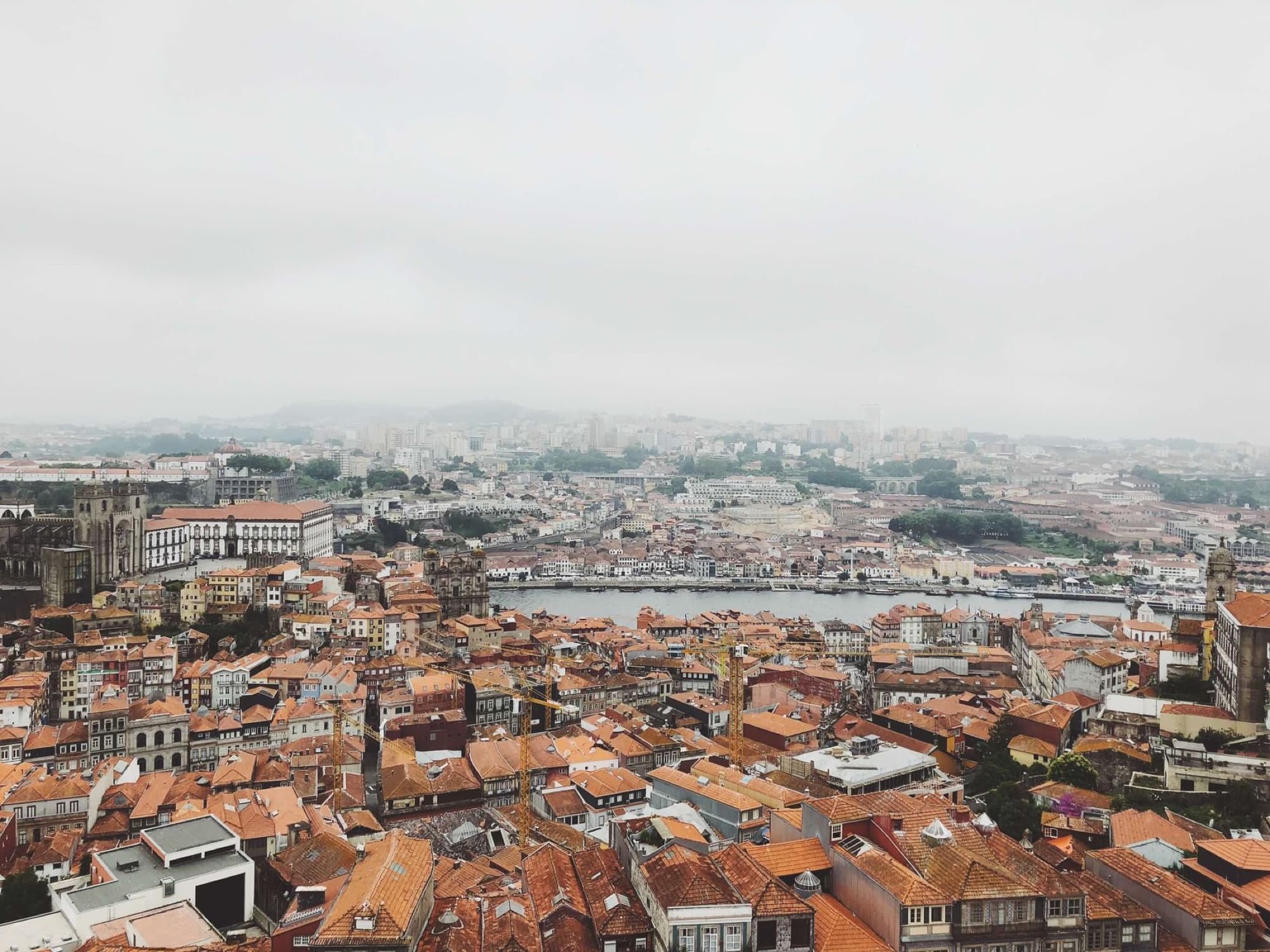 Aerial view capturing Porto's historic rooftops and Douro River under a misty sky.