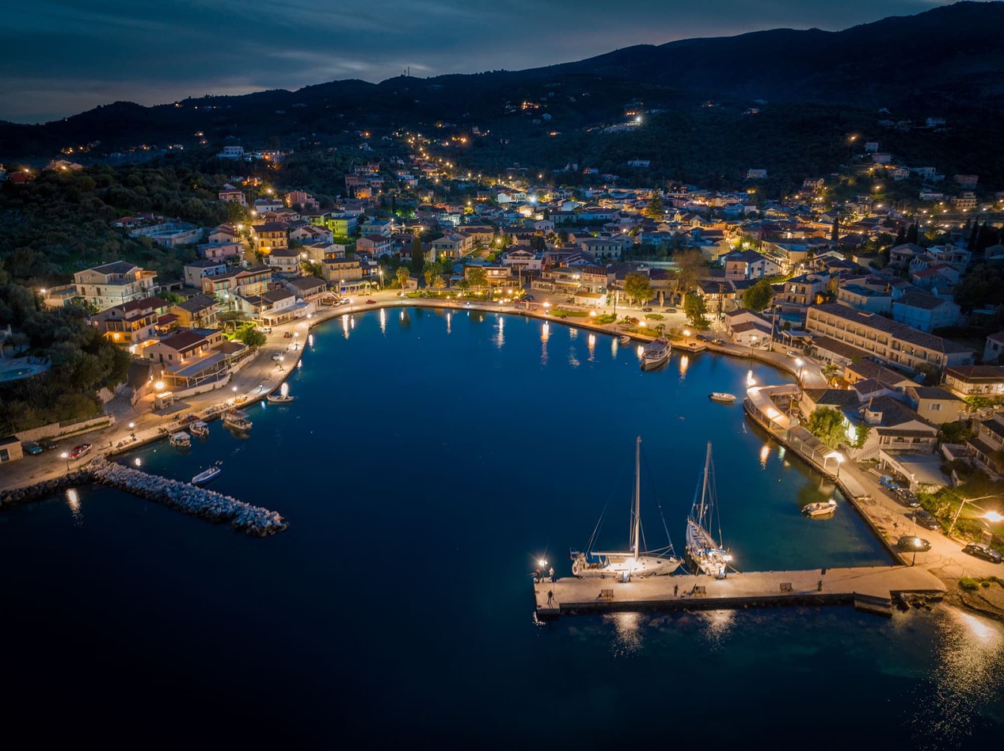 Stunning aerial night view of illuminated harbor and town in Κέρκυρα, Greece.