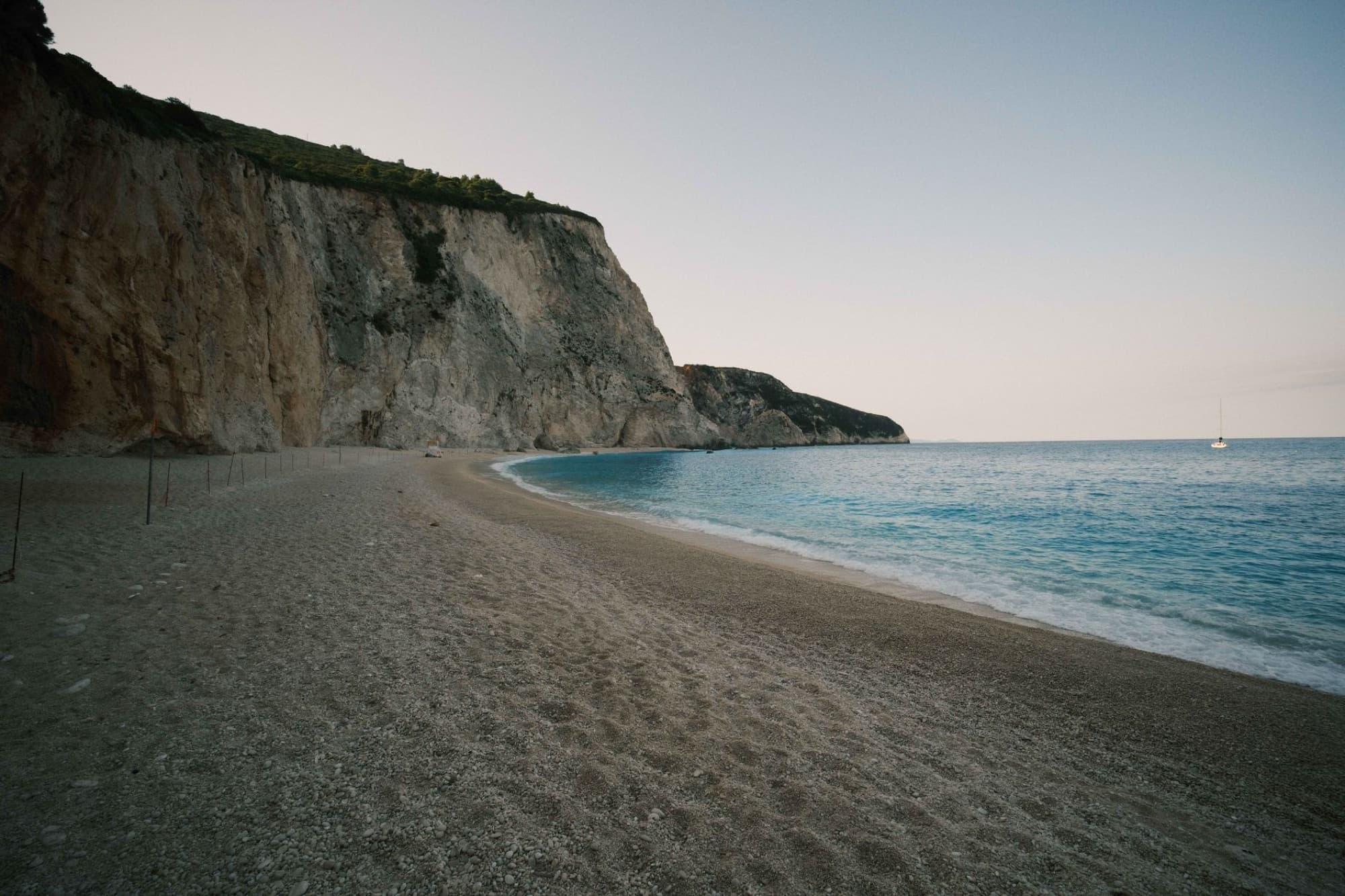 Discover the beautiful Porto Katsiki Beach in Lefkada, Greece, with its serene cliffs and clear waters during sunset.