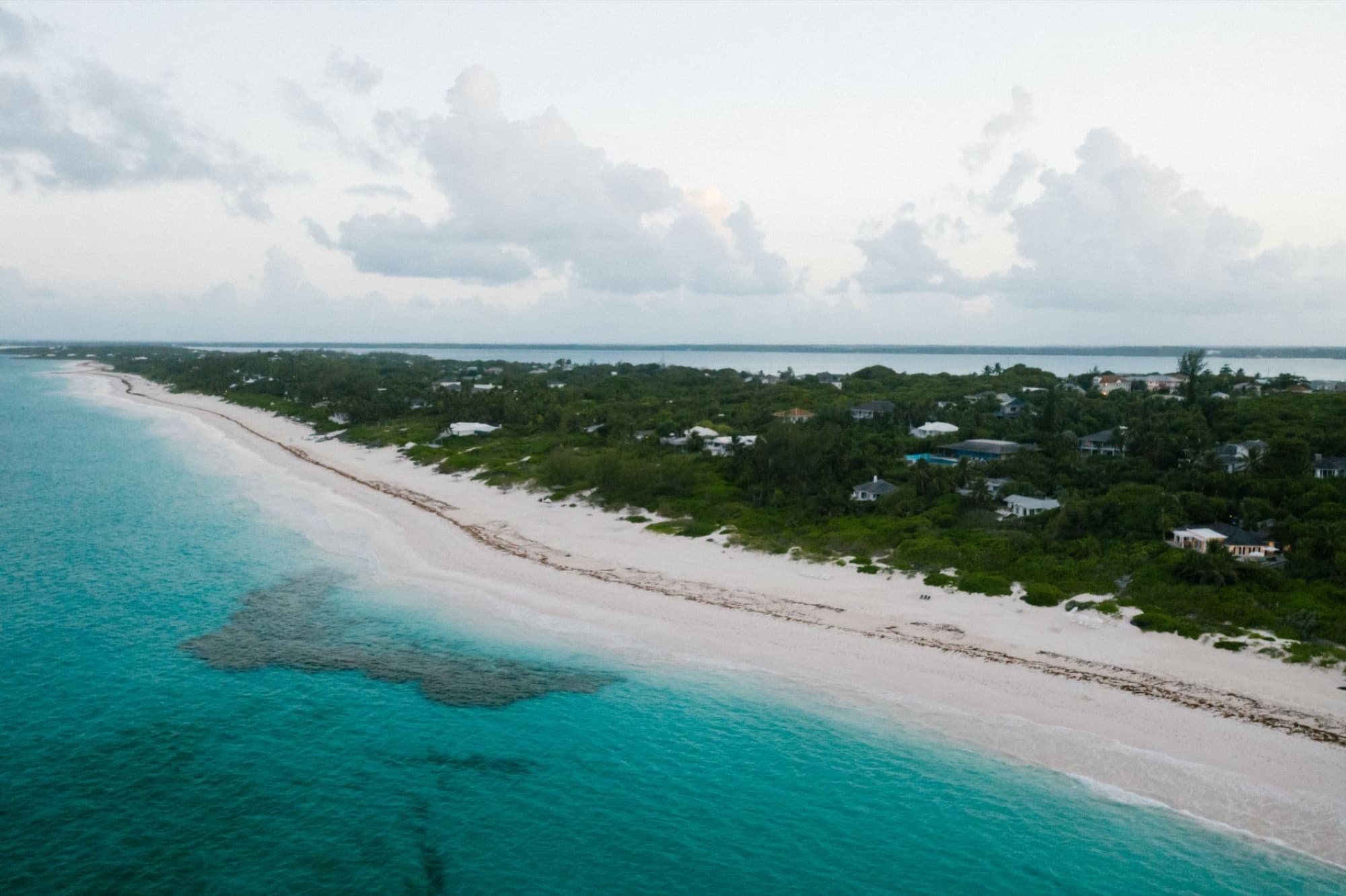 Tranquil aerial view of a lush tropical coast with turquoise waters and white sandy beach.