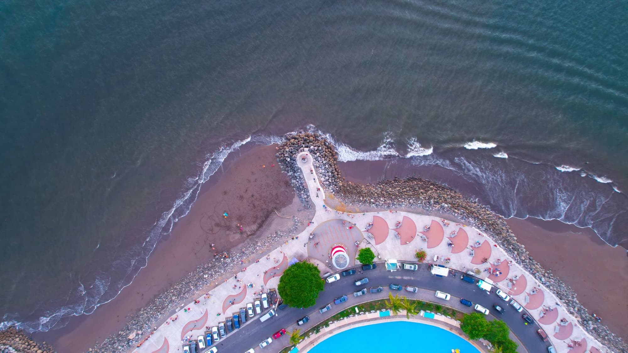 Aerial shot of a curved beachfront and ocean waves in Puntarenas, Costa Rica.