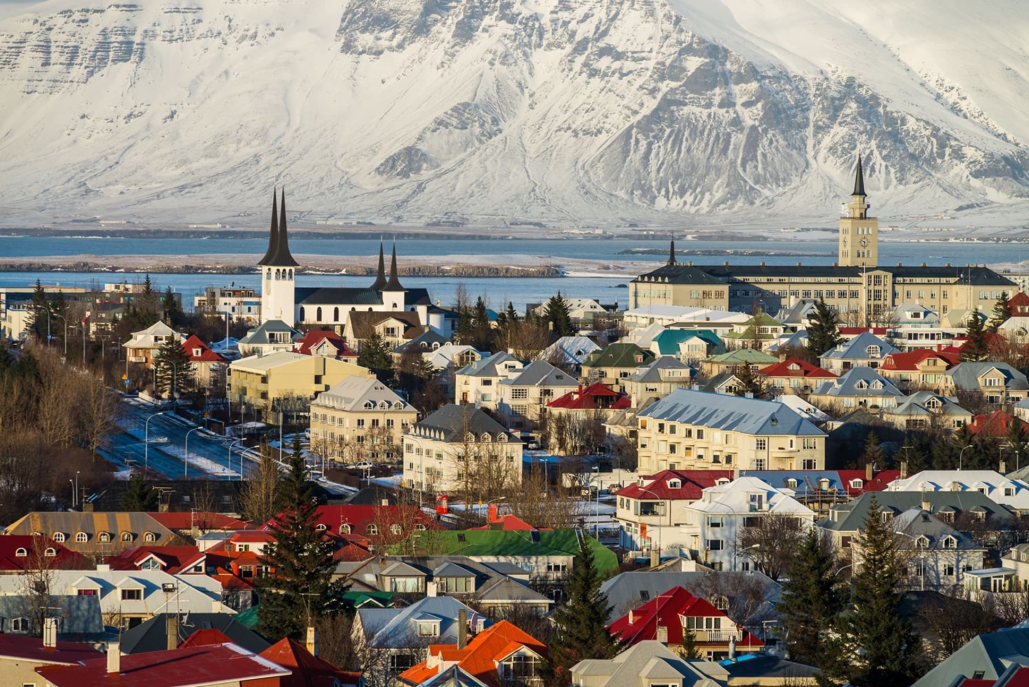 Aerial view of Reykjavik, Iceland with colorful rooftops and snowy mountains in the background.