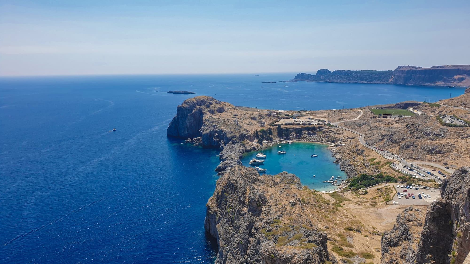 Breathtaking aerial view of St. Paul's Bay in Rhodes with turquoise waters and rocky cliffs.