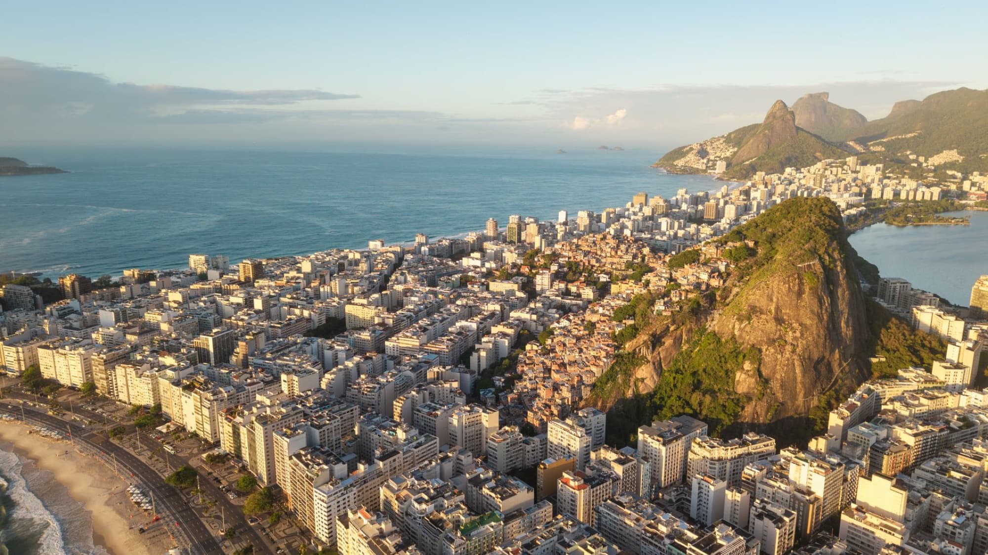 A breathtaking aerial view of Rio de Janeiro's coastline with urban landscape and mountain backdrop at sunrise.