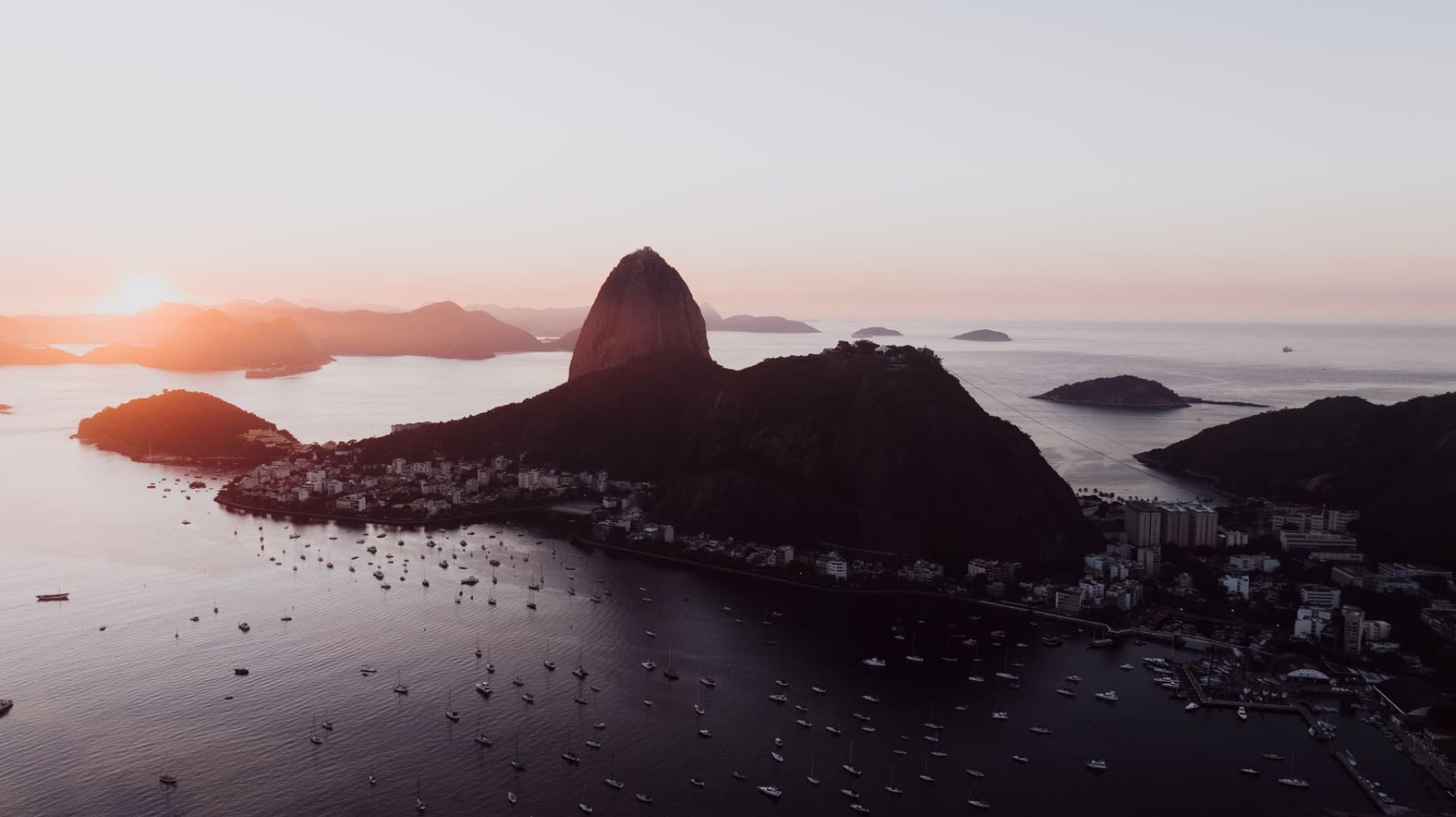 Stunning aerial shot of Rio de Janeiro's coastline with Sugarloaf Mountain at sunset.