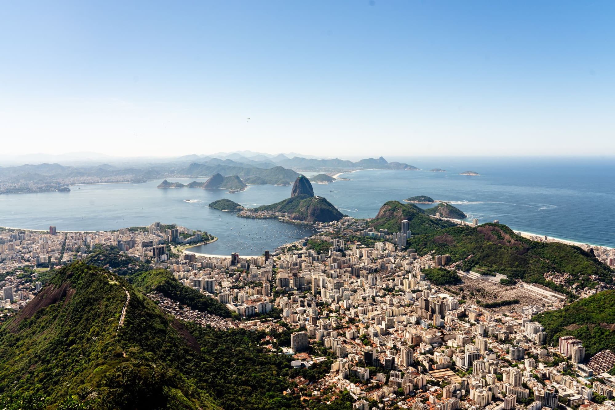 Stunning aerial view of Rio de Janeiro's cityscape with Sugarloaf Mountain and Guanabara Bay on a clear day.
