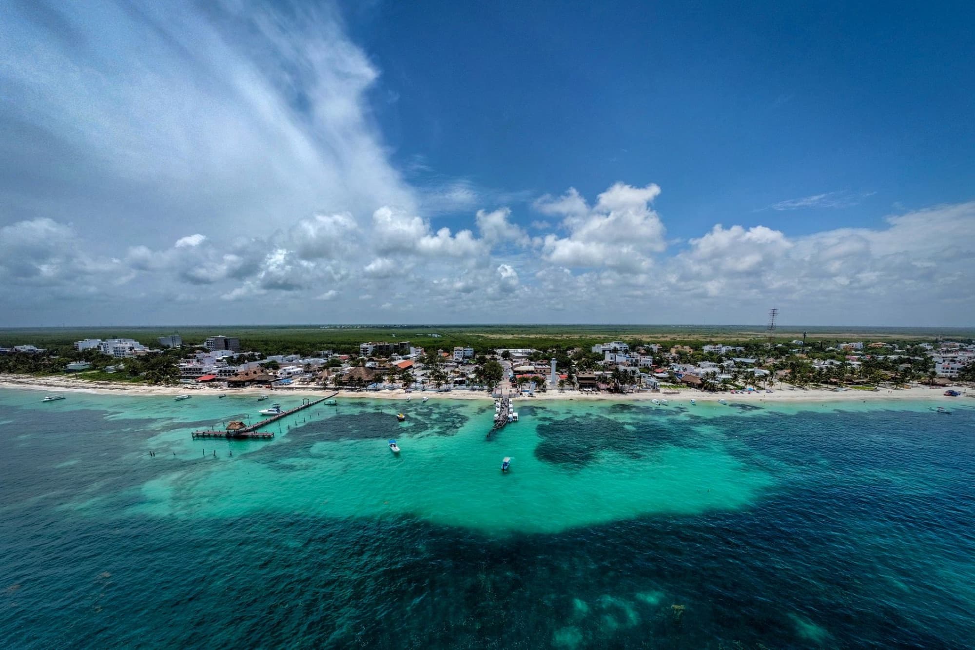 Stunning aerial view of Puerto Morelos, Mexico featuring turquoise waters and coastal town.