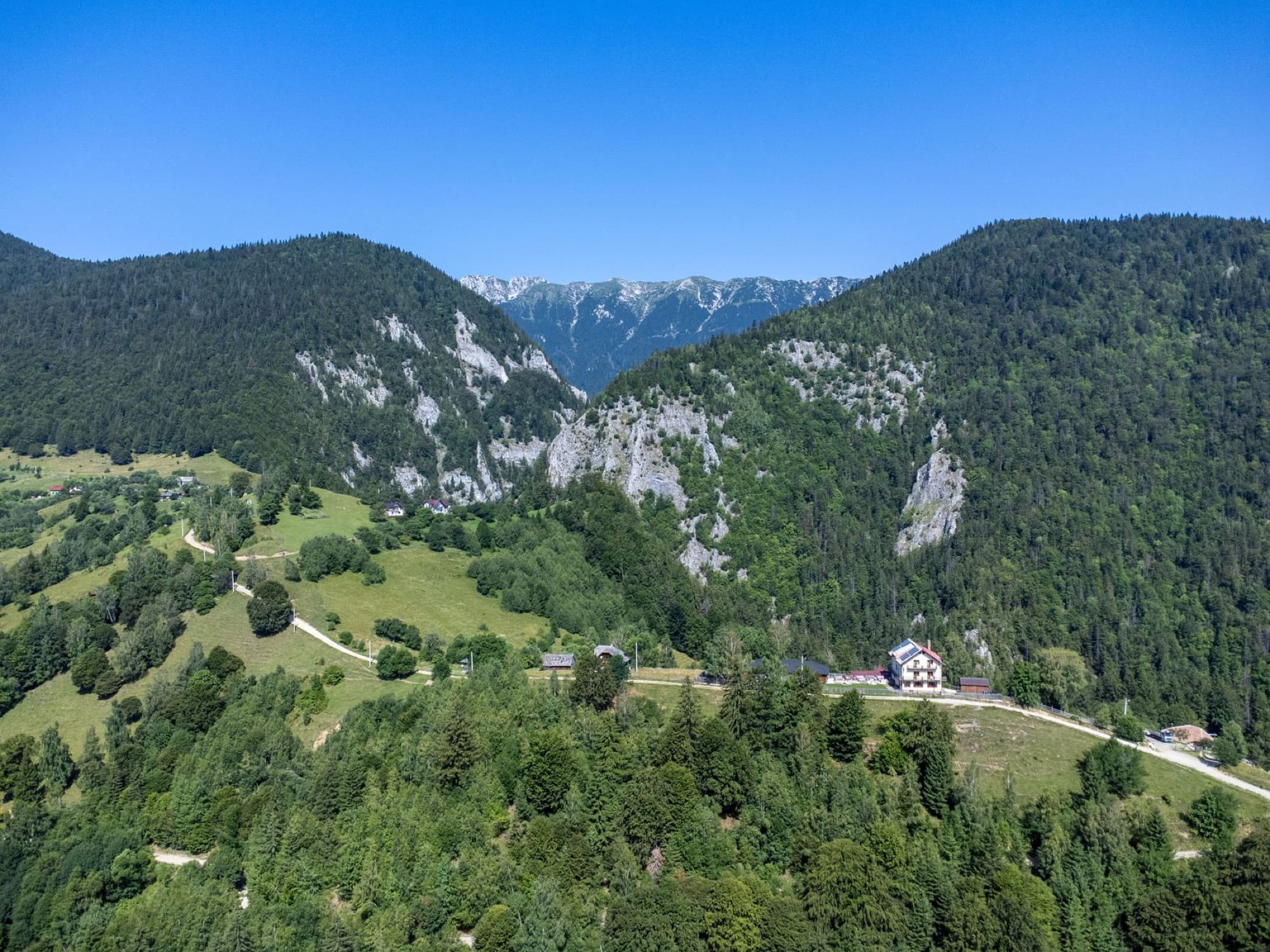 Aerial view of Măgura Village nestled in the Carpathian Mountains, Brașov, Romania on a sunny day.