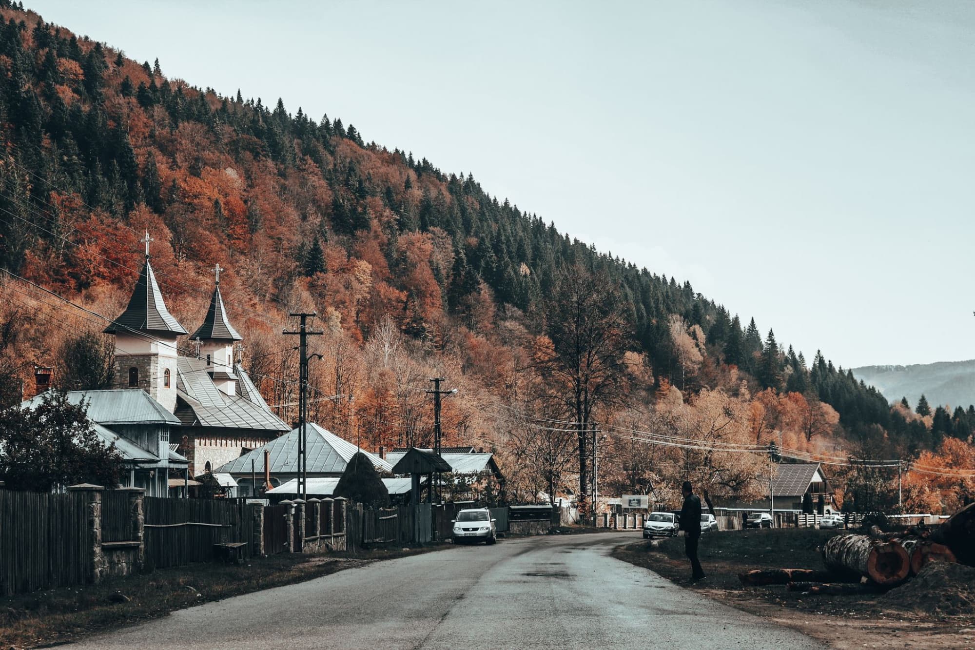 Serene autumn landscape in Romania featuring a church and picturesque village road.