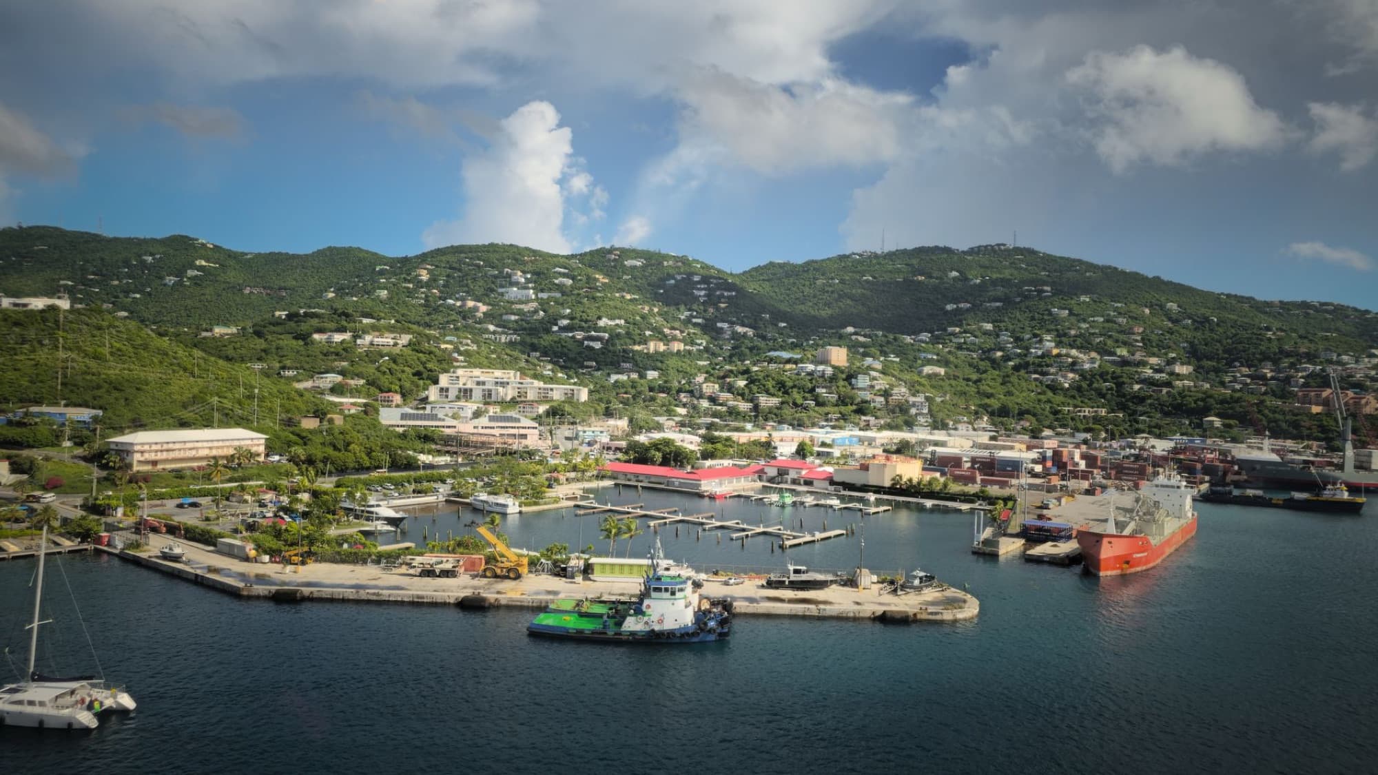 A scenic aerial view of Charlotte Amalie Harbor on St. Thomas, featuring lush green mountains and clear blue water.