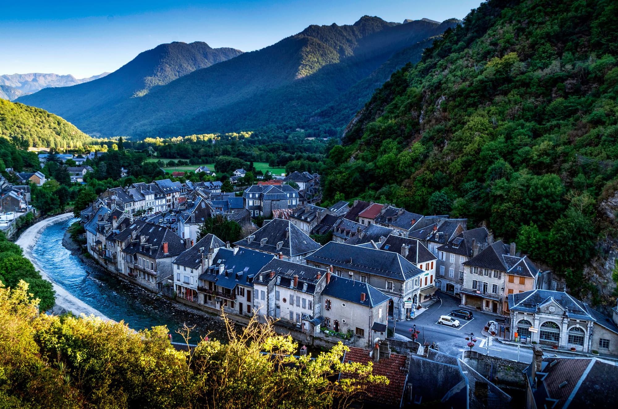 Aerial view of a picturesque French village with mountains and a winding river.