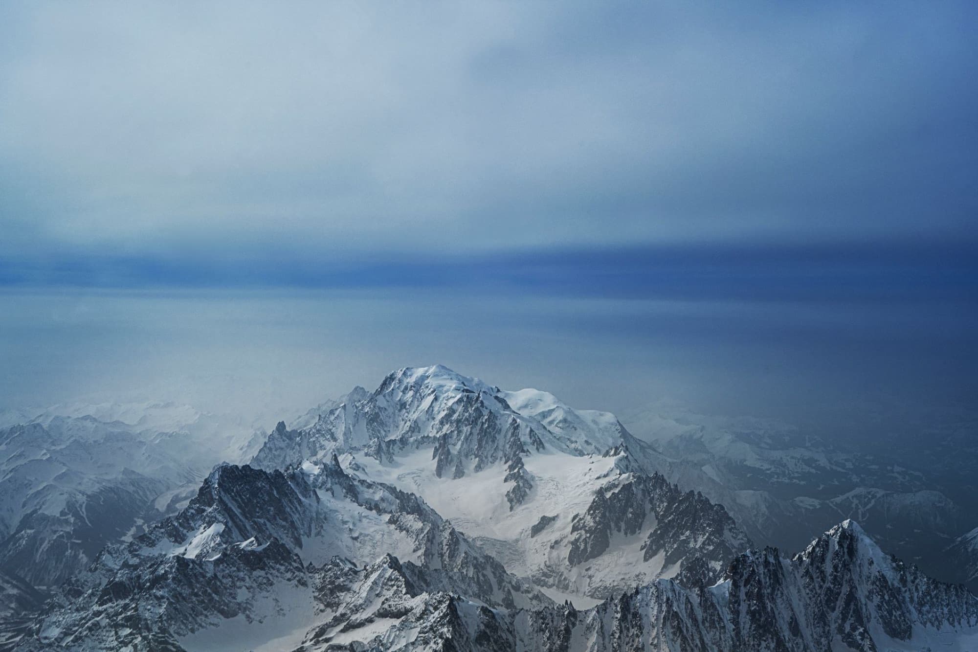 A stunning aerial view of Mont Blanc covered in snow and ice under a blue sky.