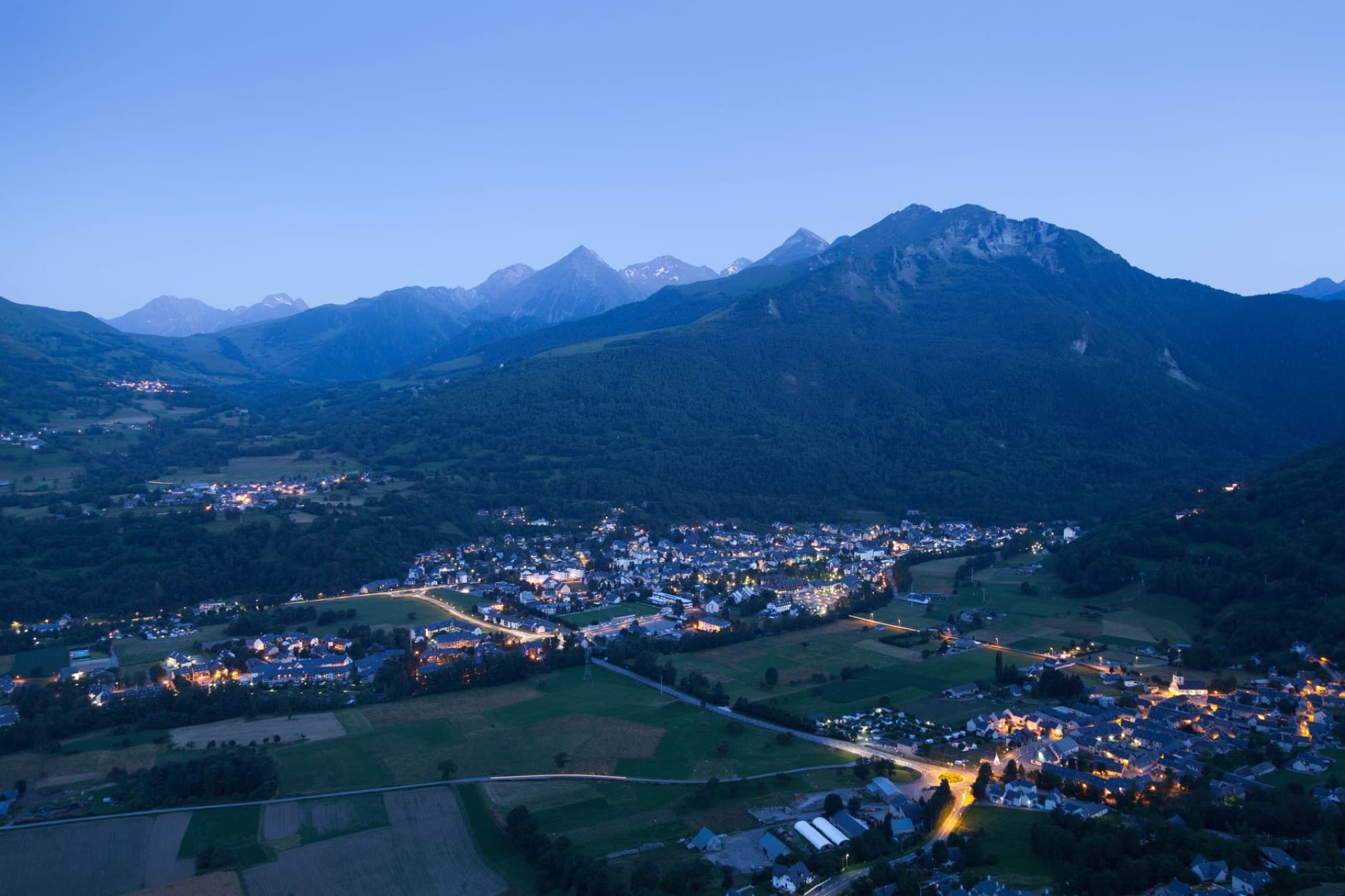 Scenic aerial panorama of Luz-Saint-Sauveur in France, illuminated at twilight against the Pyrenees mountains.