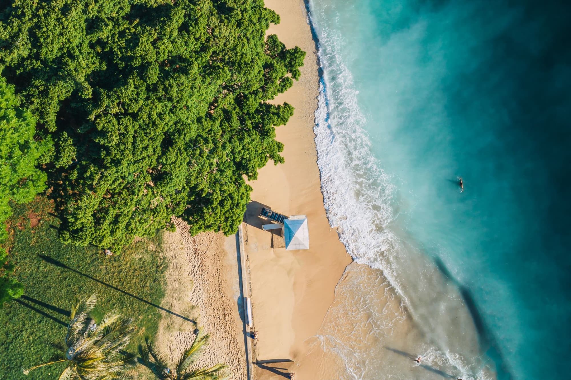 Breathtaking aerial view of a sandy beach with a lifeguard post and ocean waves.