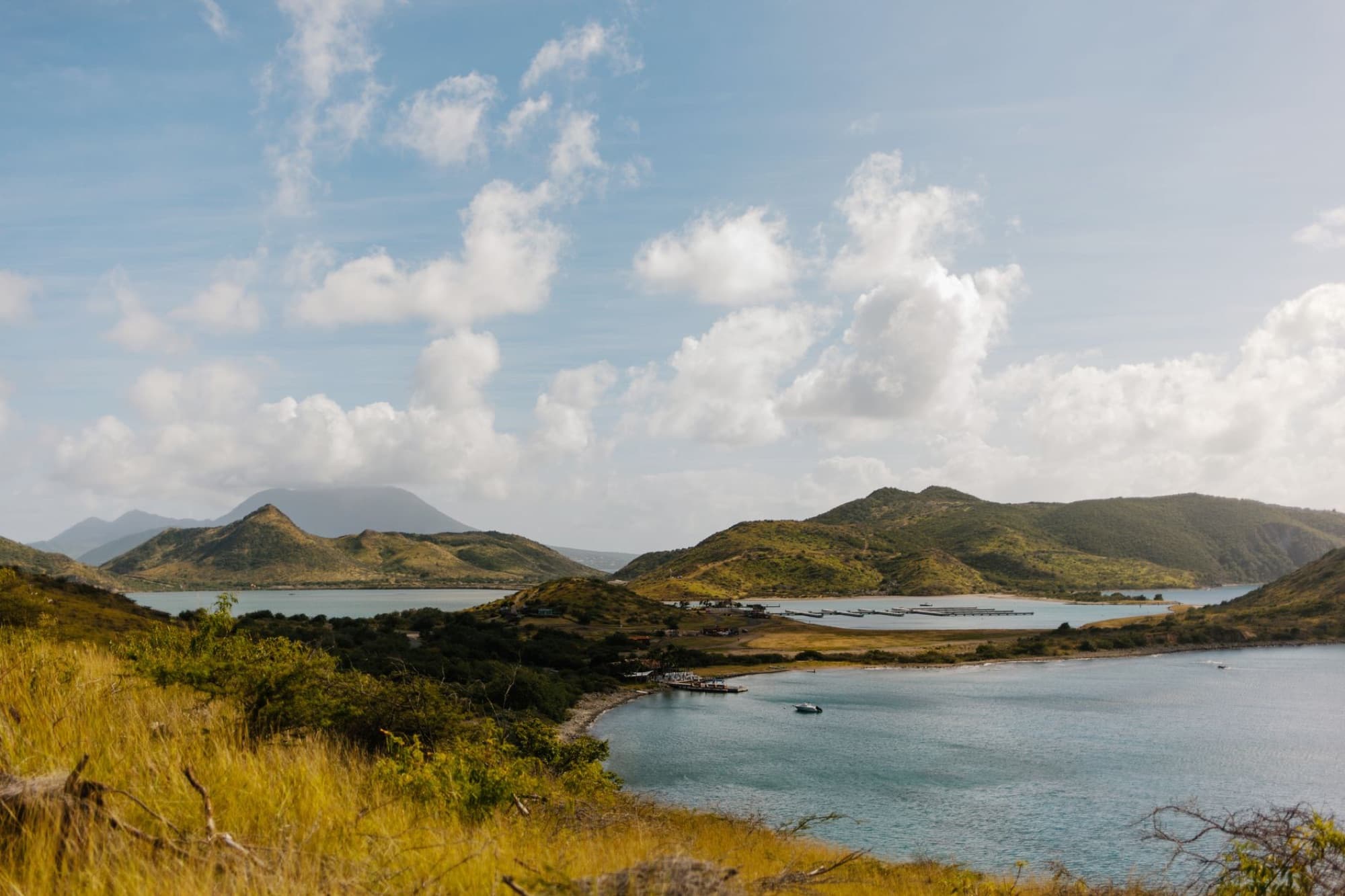 Idyllic island landscape featuring a lake, mountains, and a vibrant blue sky.